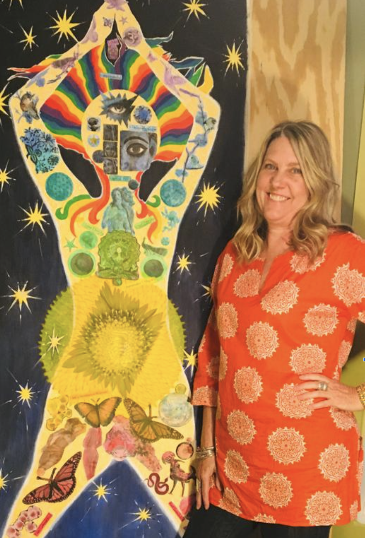 A woman with blonde wavy hair, wearing an orange dress with pink circular patterns, smiling and standing next to a colorful collage of various images in a human figure shape. The collage includes eyes, animals, planets, butterflies, and other artistic elements, set against a dark background with yellow star-like shapes.
