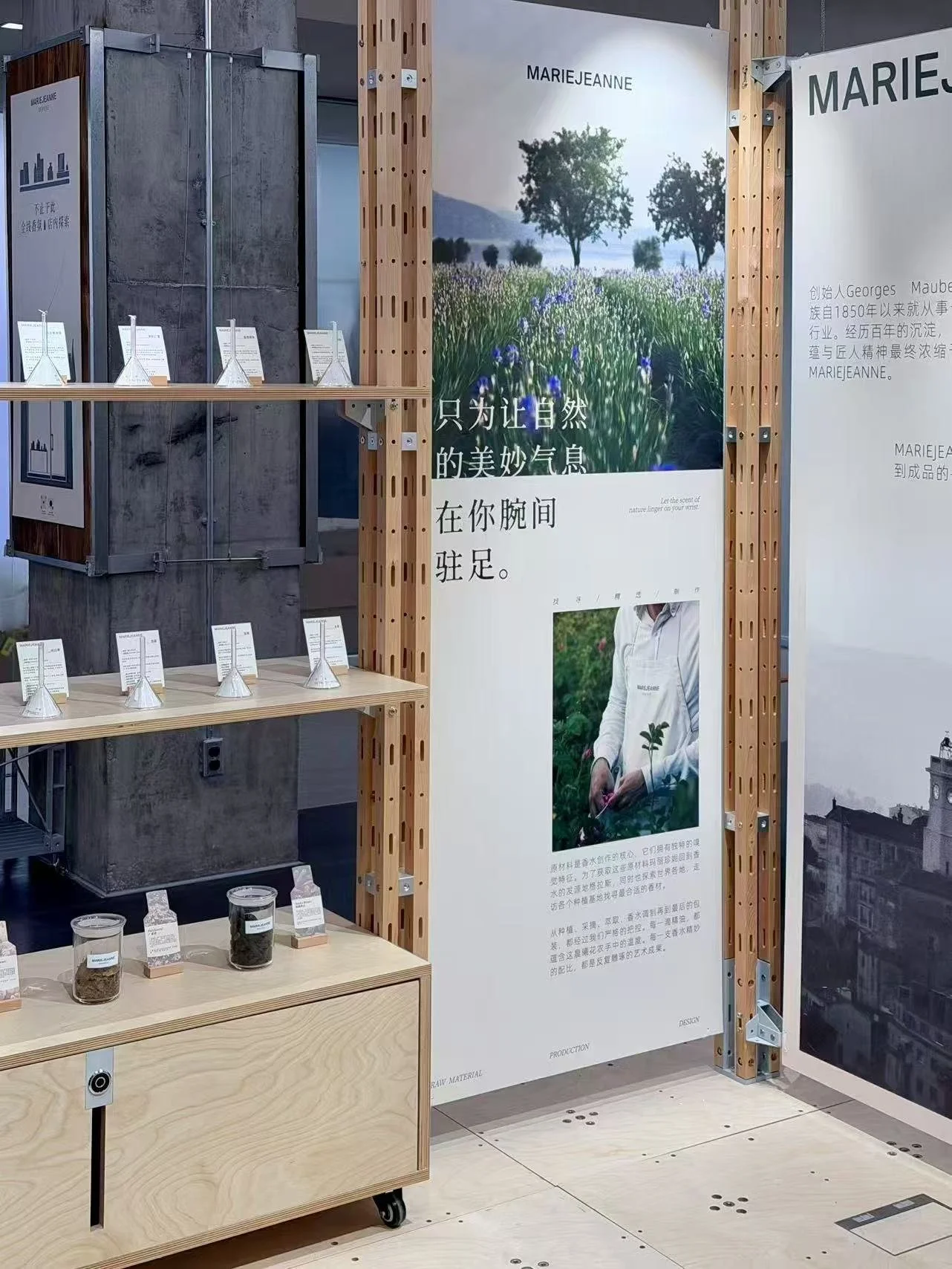 A display area with informational posters about a person named Marie Jeanne, featuring images of a field with trees and a person inspecting plants, along with small jars containing plant samples on a wooden cart.