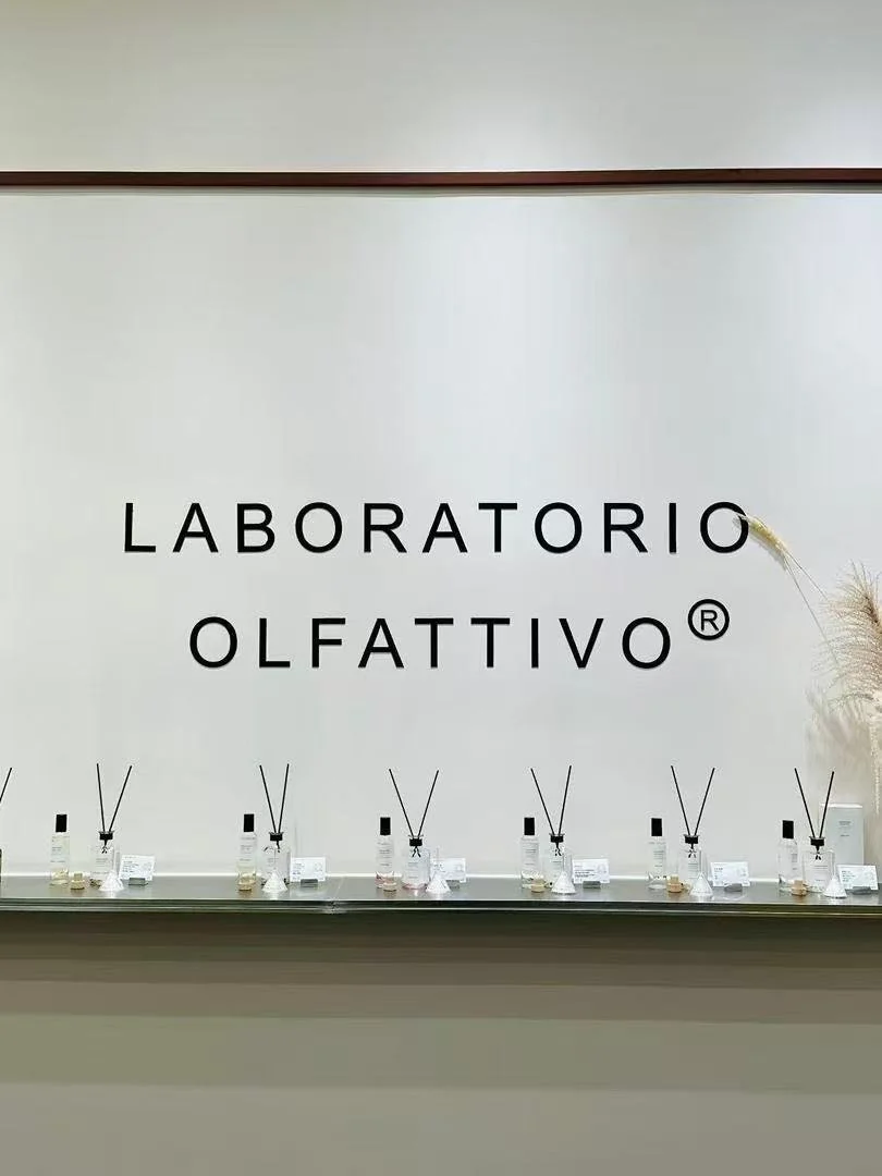 Display of various perfume or fragrance bottles at a laboratory named 'Laboratorio Olfattivo' in a minimalist setting.