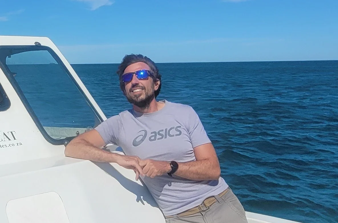 Man with sunglasses leaning on boat railing on the ocean