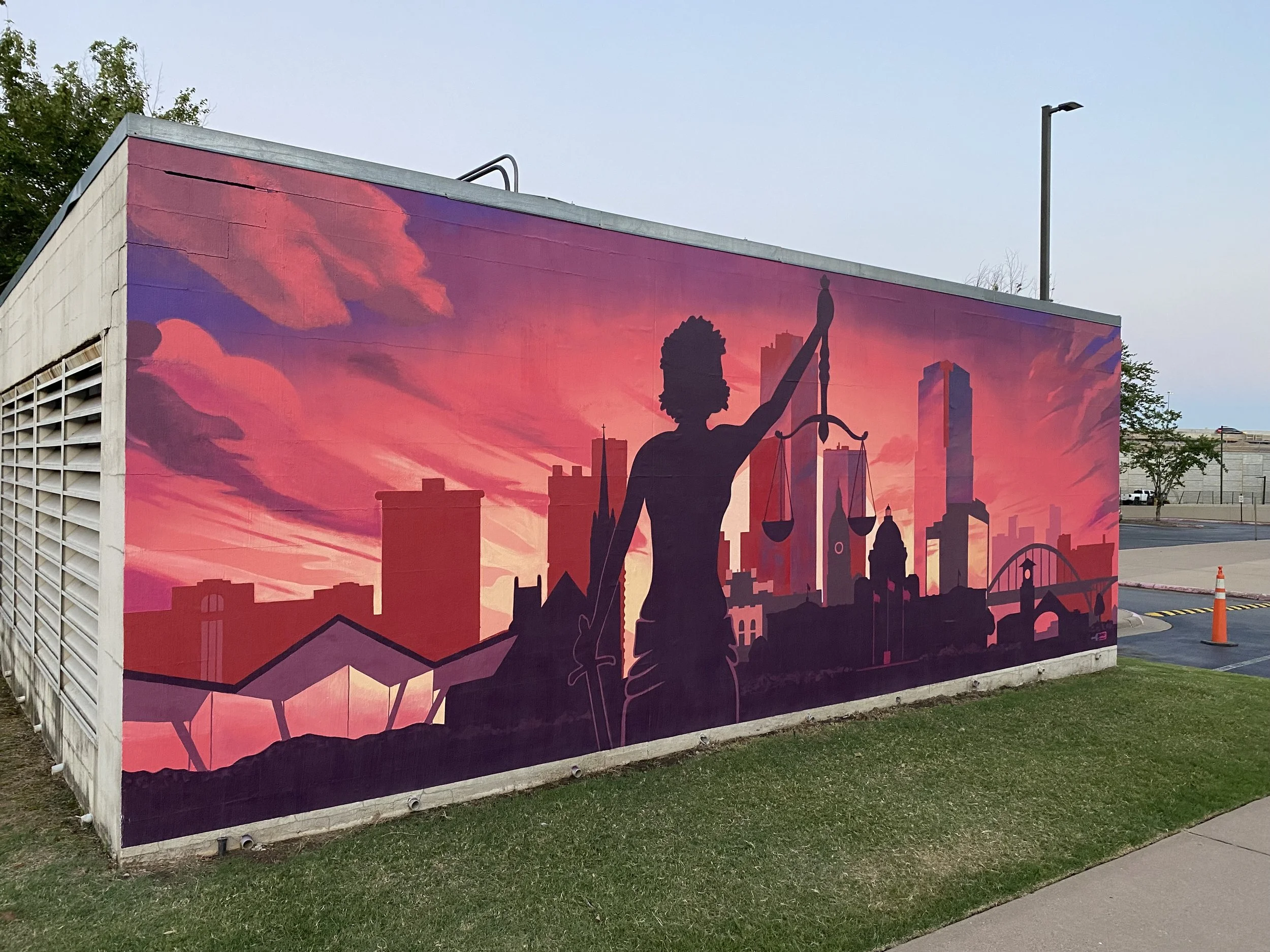 Brightly colored pink and purple mural of Lady Justice and Little Rock Skyline on UALR Bowen School of Law building