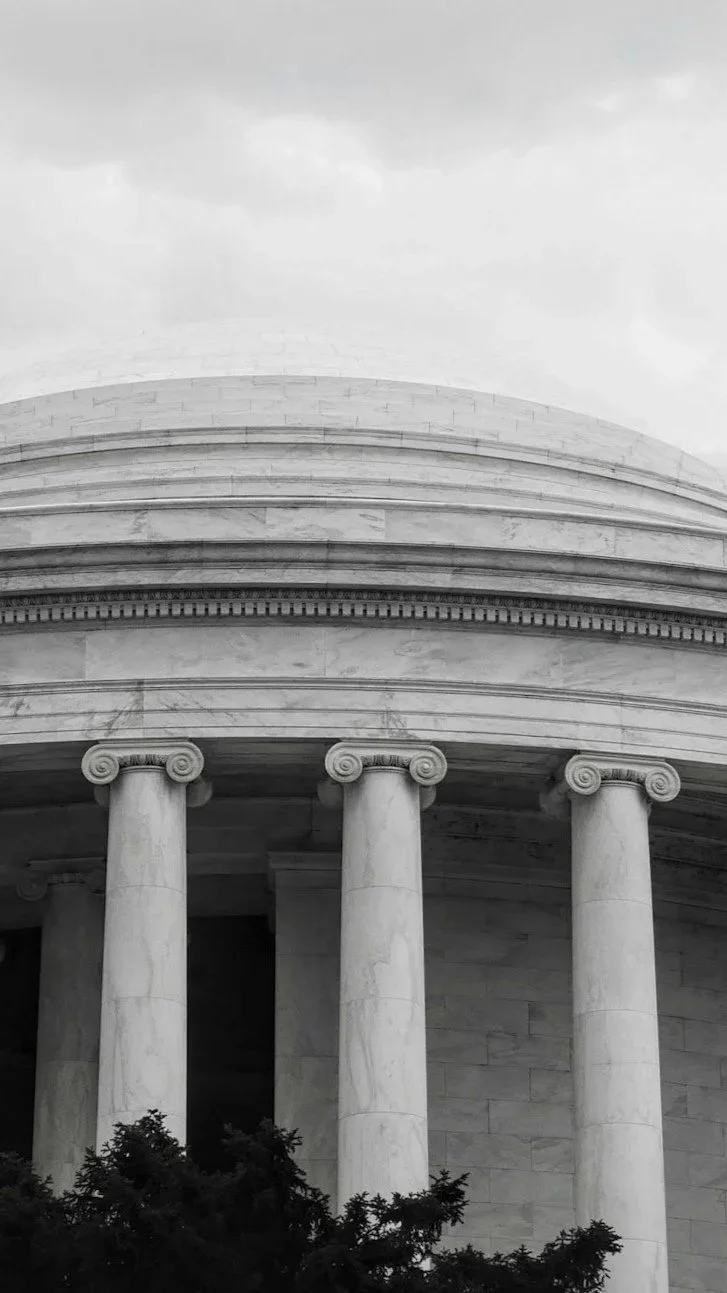 Close-up of a neoclassical building with large columns and detailed architectural features, in black and white.