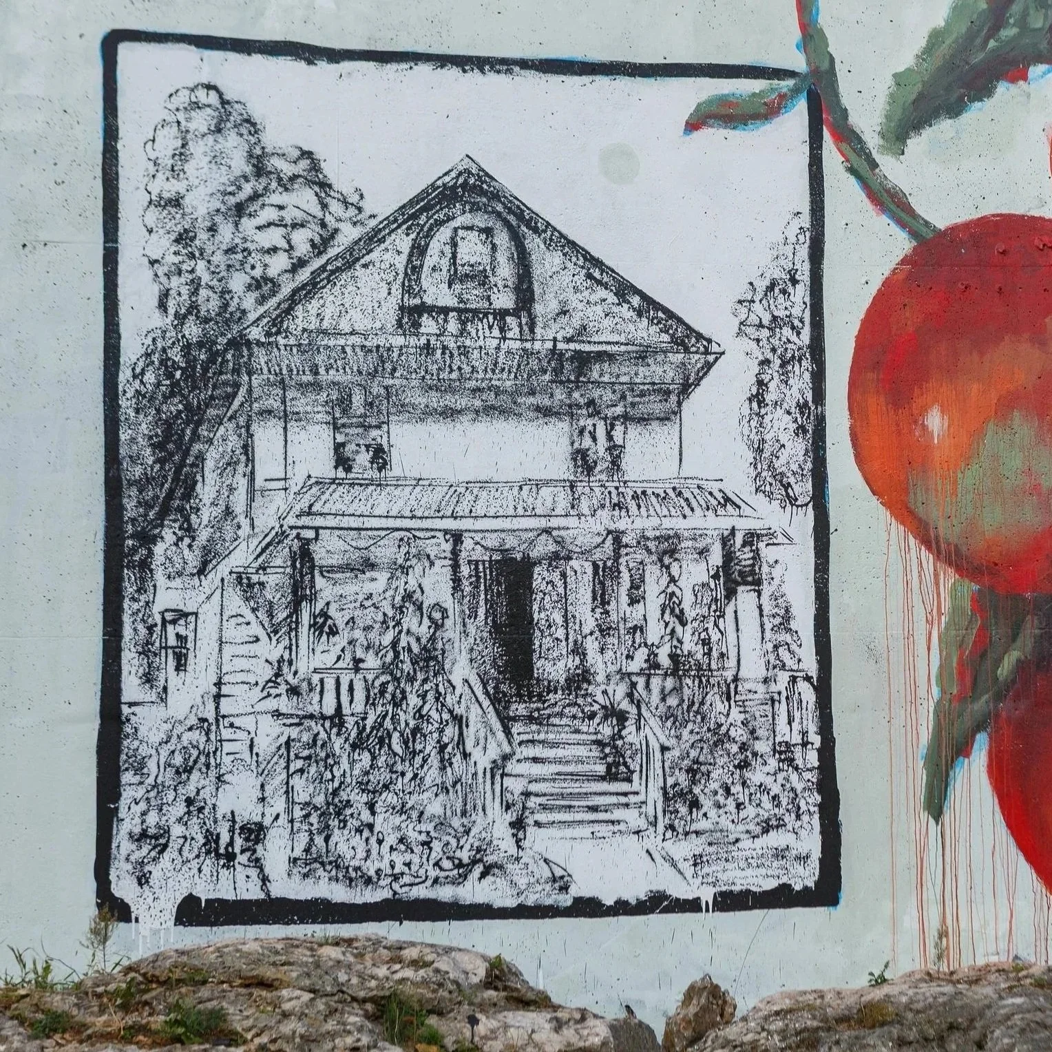 Black and white spray paint mural of a house on a wall.