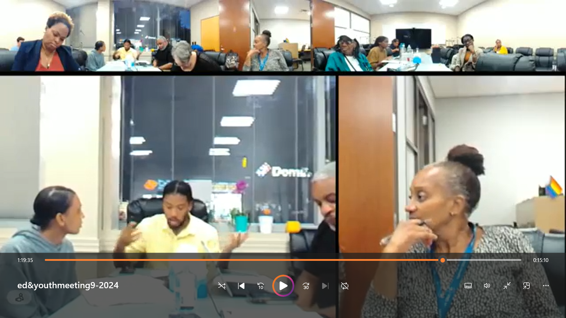 Photo of a virtual meeting showing multiple people in different locations on a video conference call, with a mix of men and women engaged in discussion.