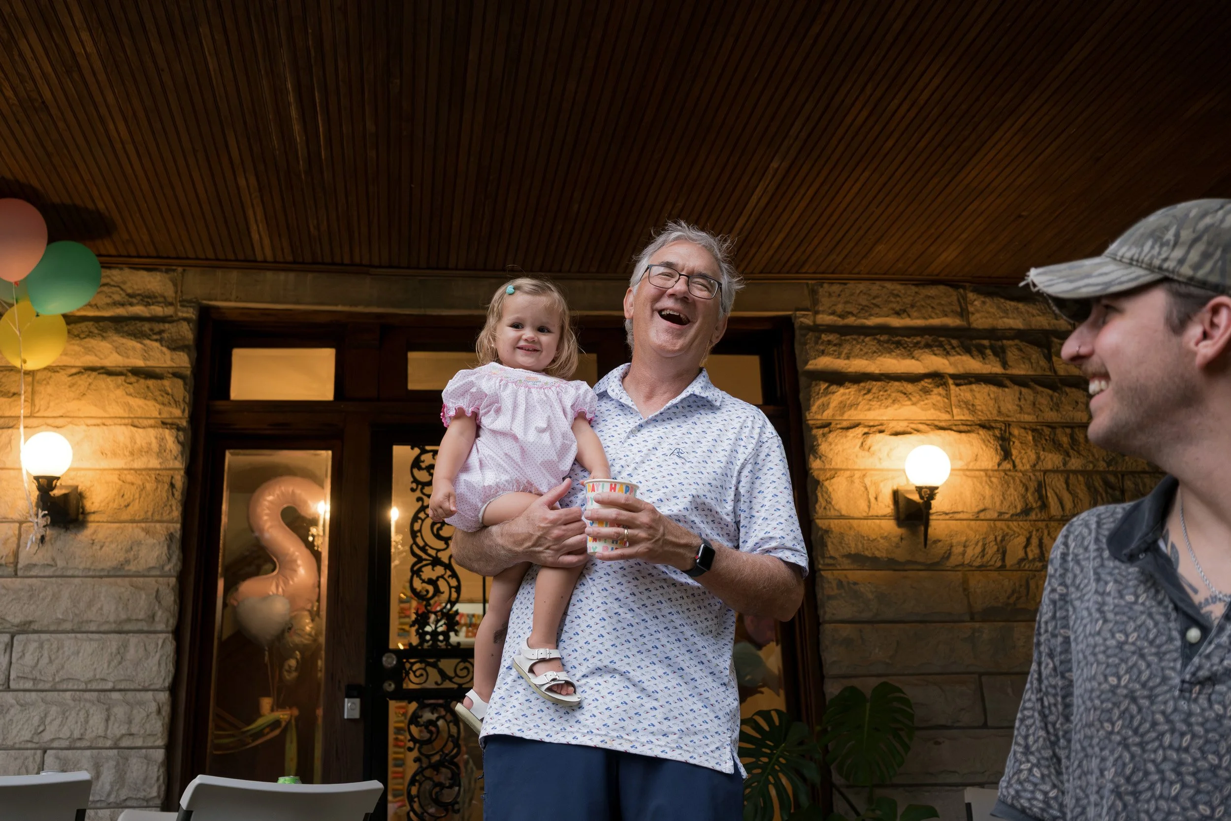 A man holding a young girl at a celebration with balloons and decorations.
