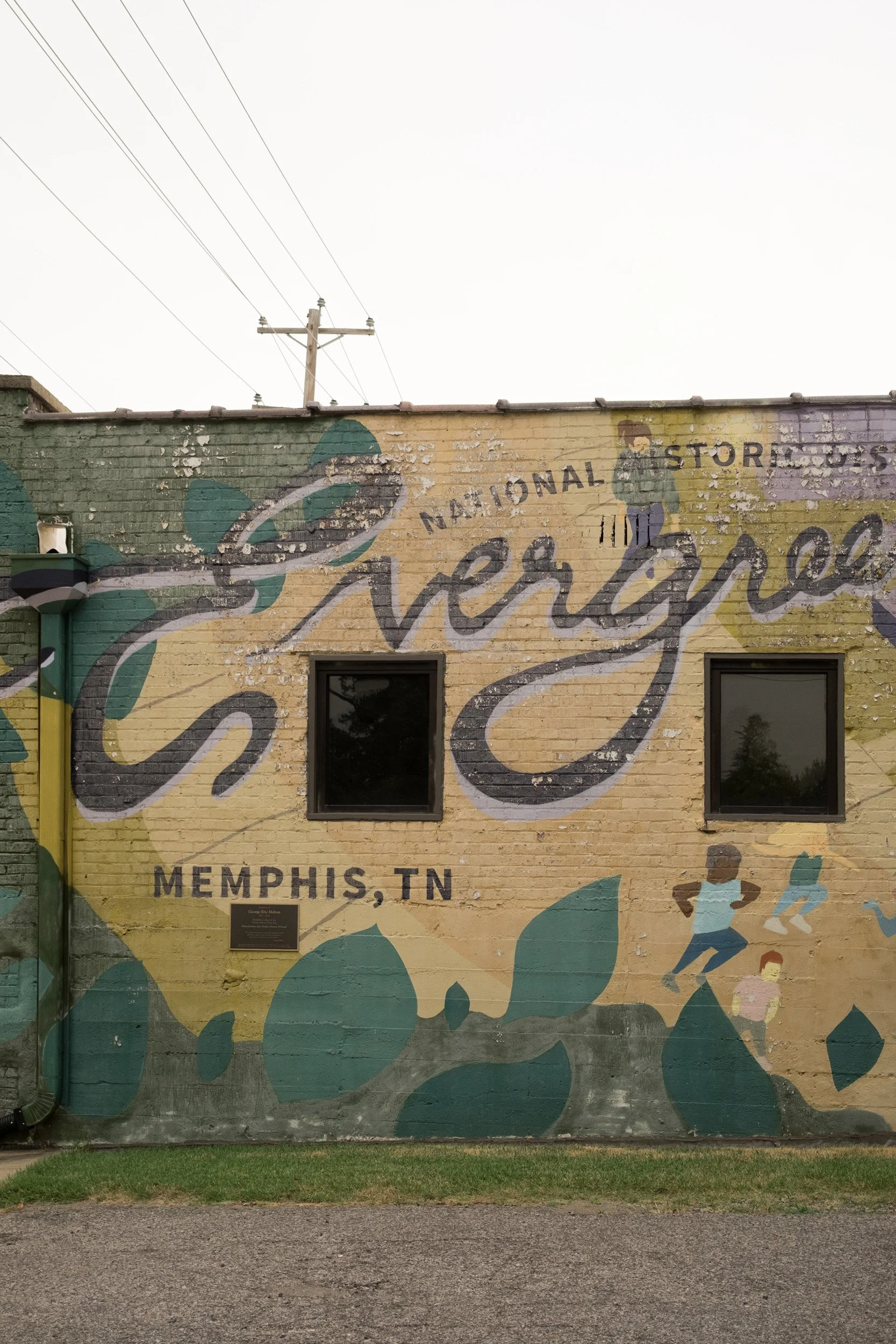 Murals on a brick building in Memphis, Tennessee, featuring abstract designs and the words 'National Store' with part of a large cursive word and some illustrations of people.