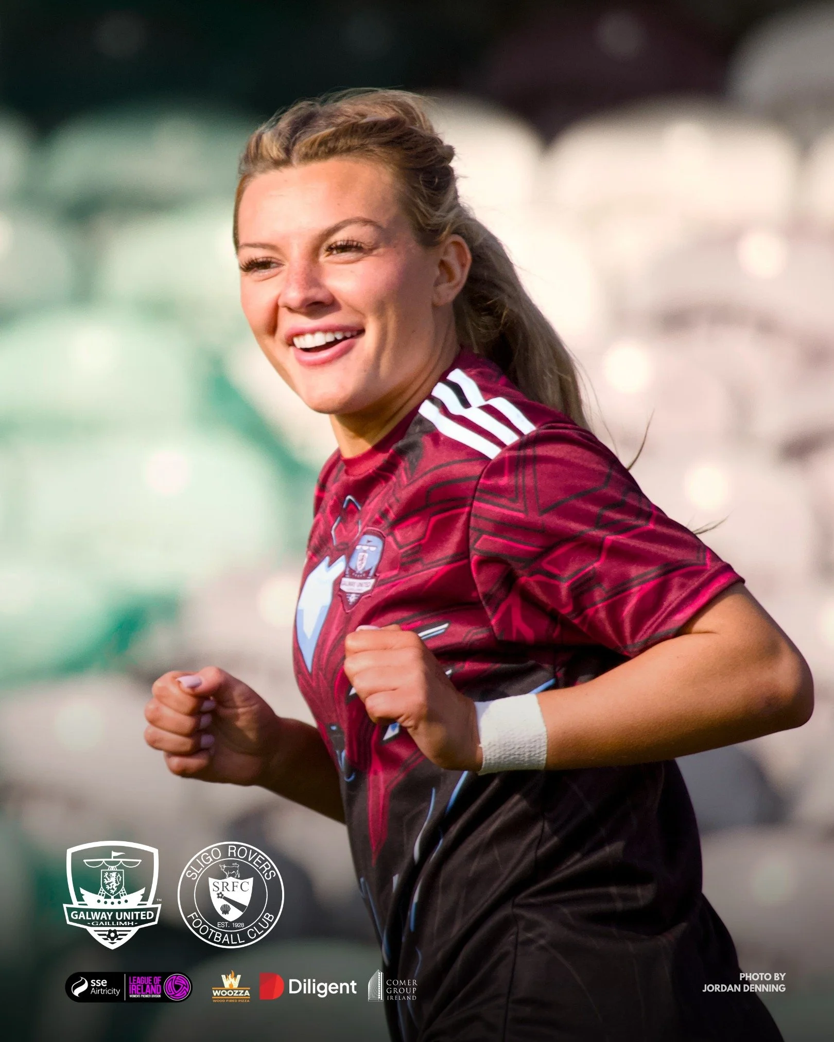 A female soccer player with long hair in a ponytail, wearing a maroon and black jersey, running on a field.