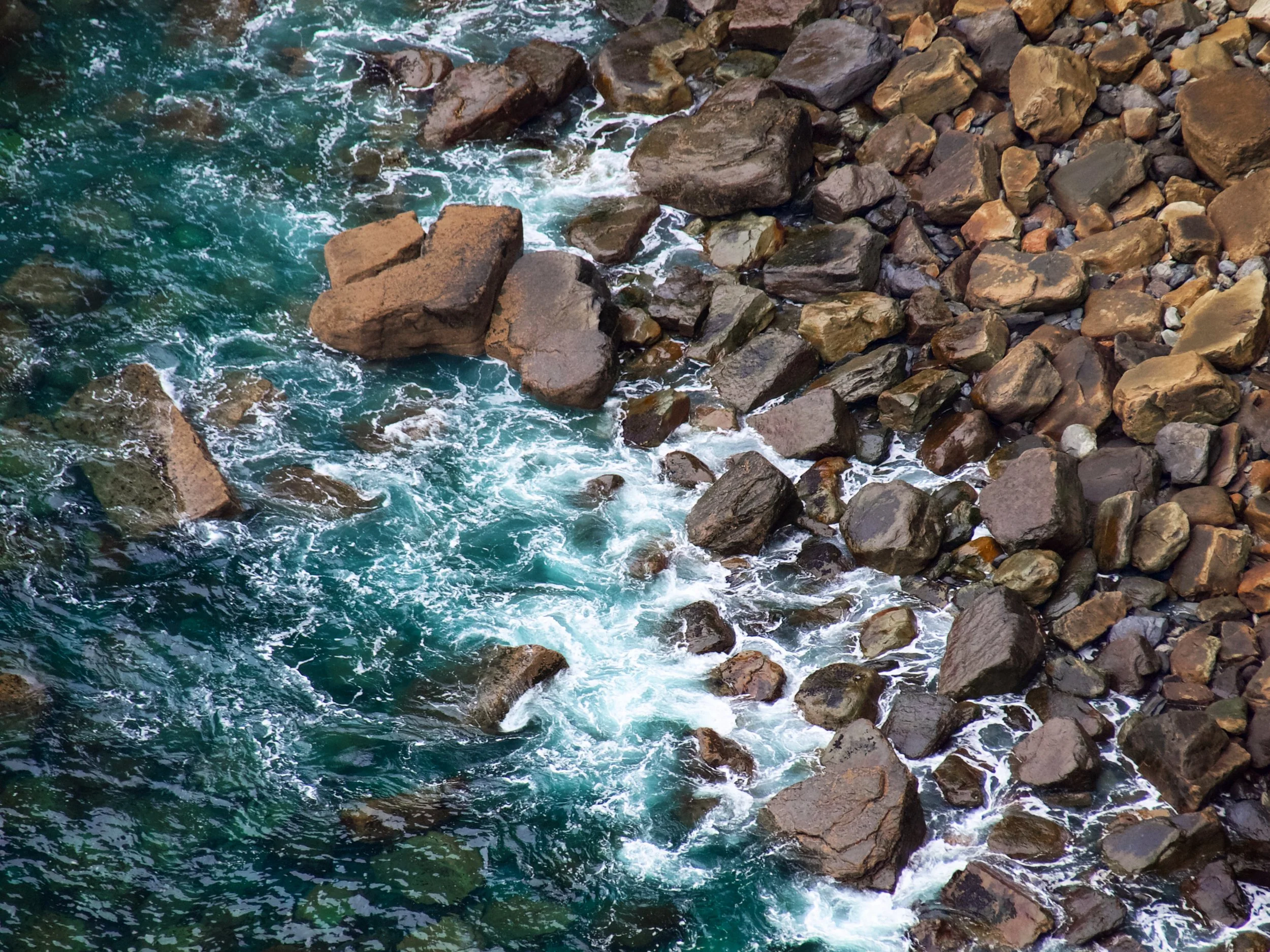 Rocks by a body of water with waves crashing against them.