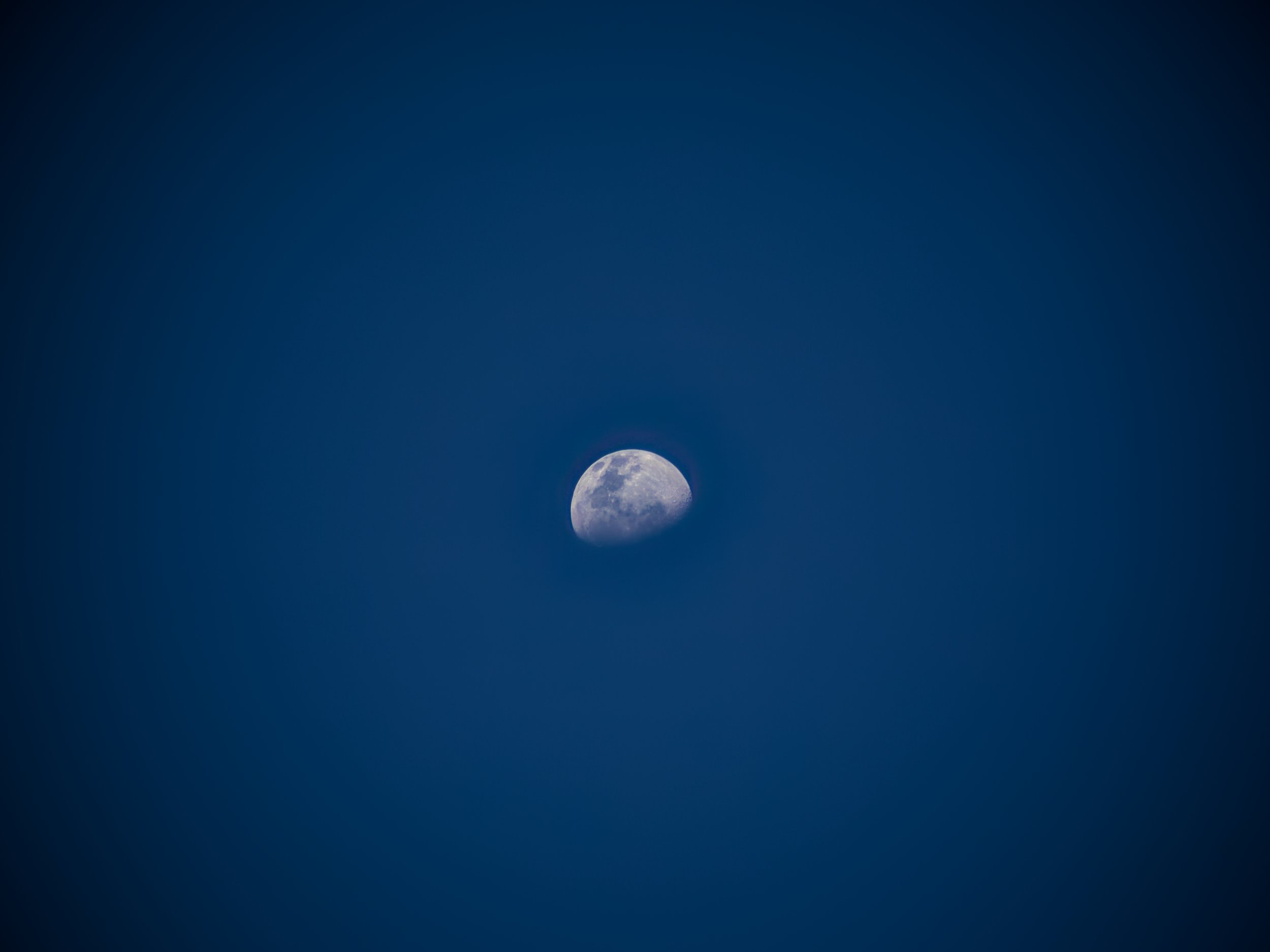 The image shows a full moon in the night sky with a dark blue gradient background.