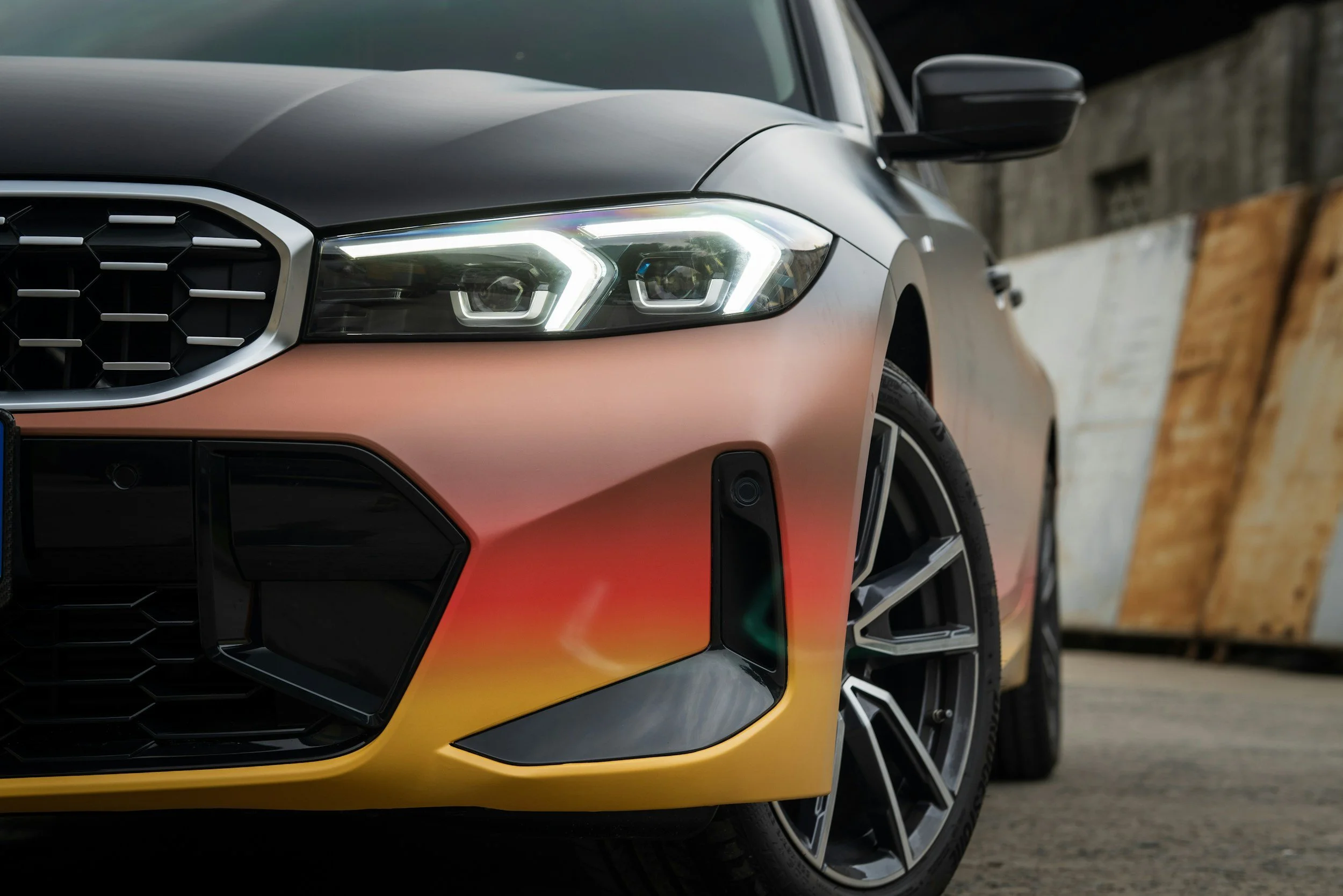 Close-up of a sedan with an orange-to-black gradient color-change vinyl wrap