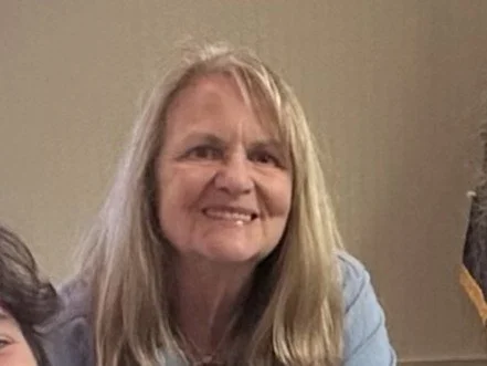 Smiling woman with long blonde hair wearing a light blue top.