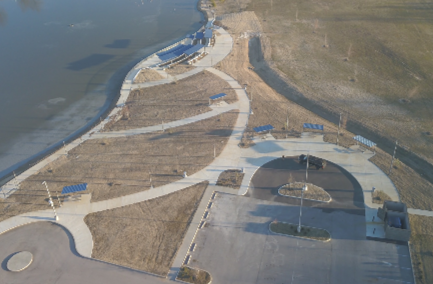 Aerial view of a park with winding pathways, some benches, and a water body nearby.