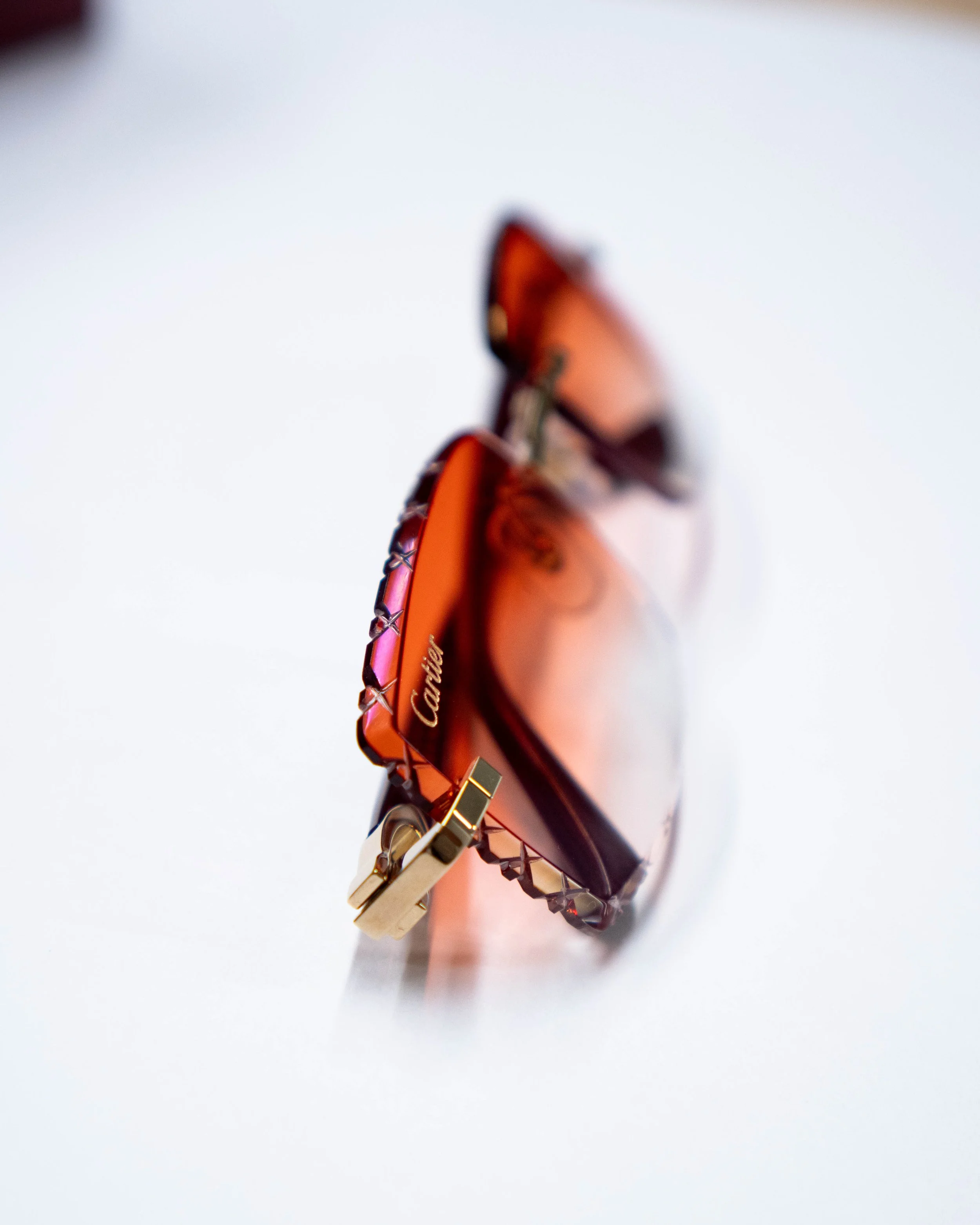 Close-up of a rose gold Cartier bracelet with gemstone accents resting on a white surface.