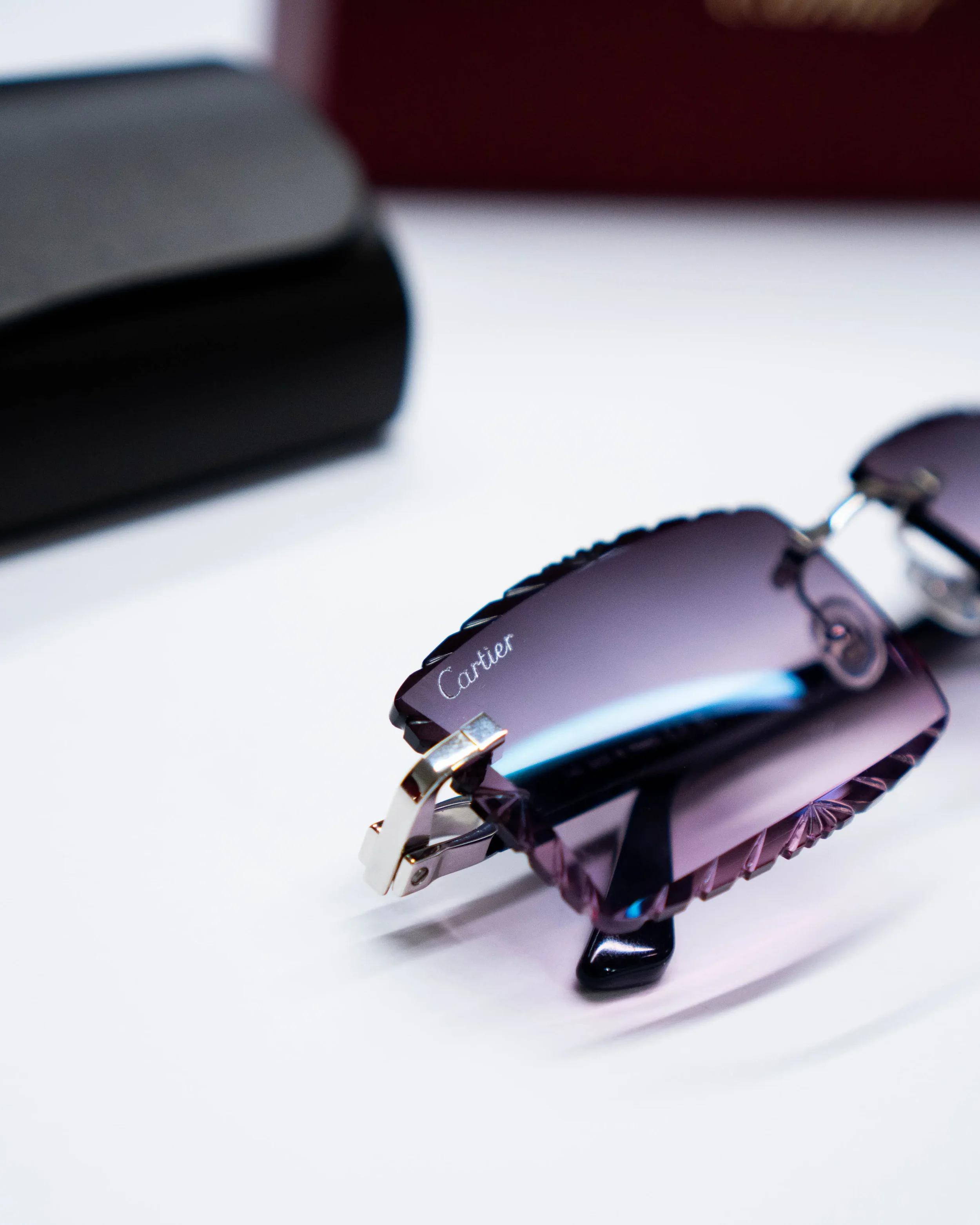 Close-up of a Cartier watch with a purple metallic band on a white surface, partially visible.