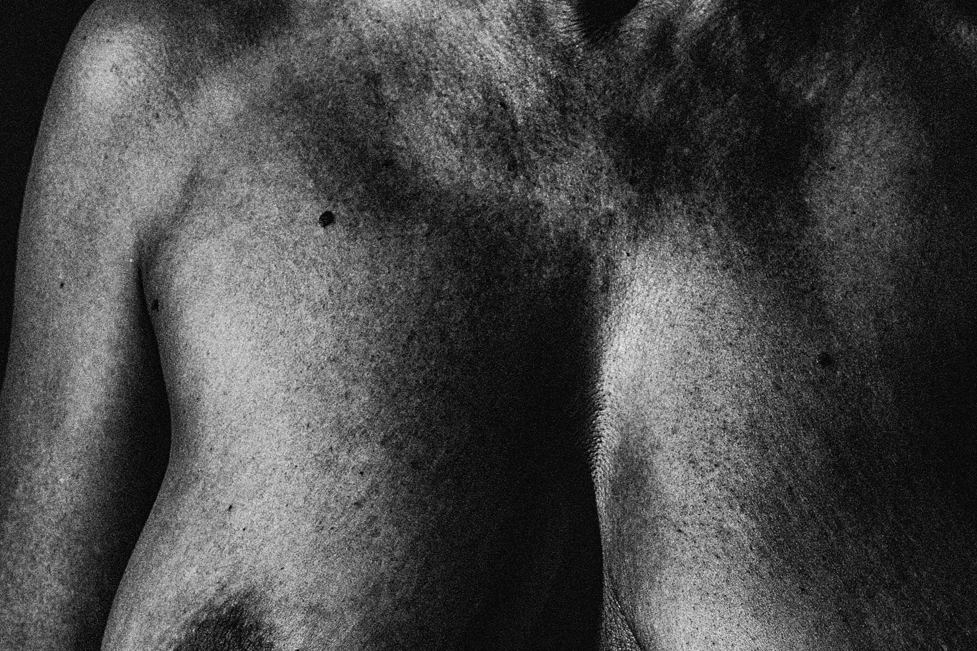Black and white close-up of a woman's shoulder, chest, and neck area, showing textured skin. Nude Art Photography by Vlad Goth.