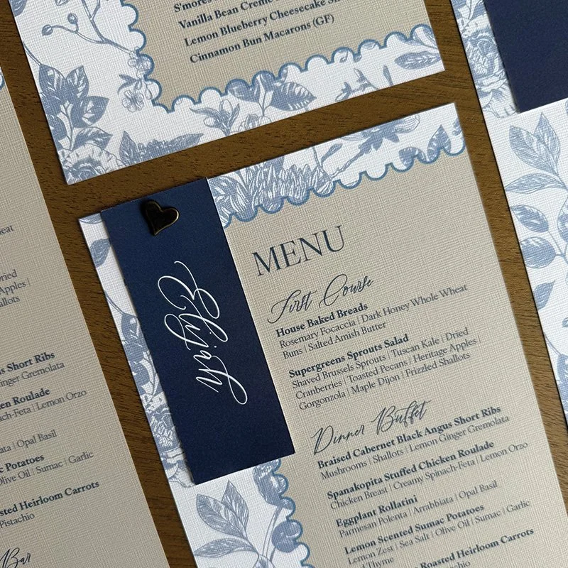 Coordinating navy and ivory wedding menus with elegant typography and blue botanical details.