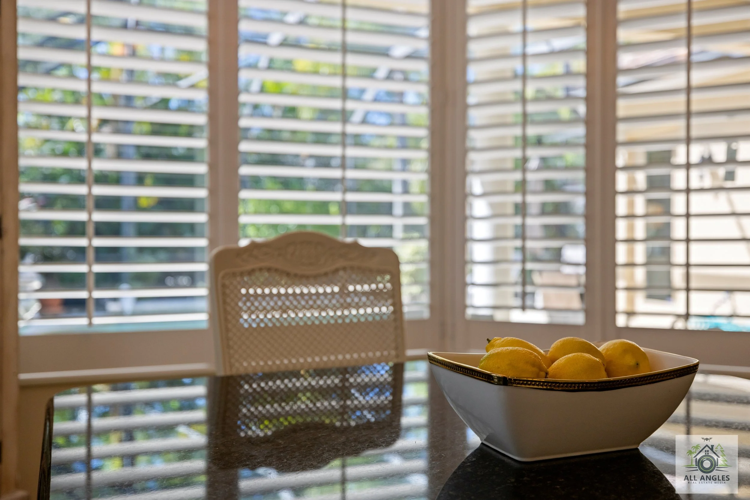 Occupied home staging kitchen table with white with gold trimmed bowl full of lemons accessory