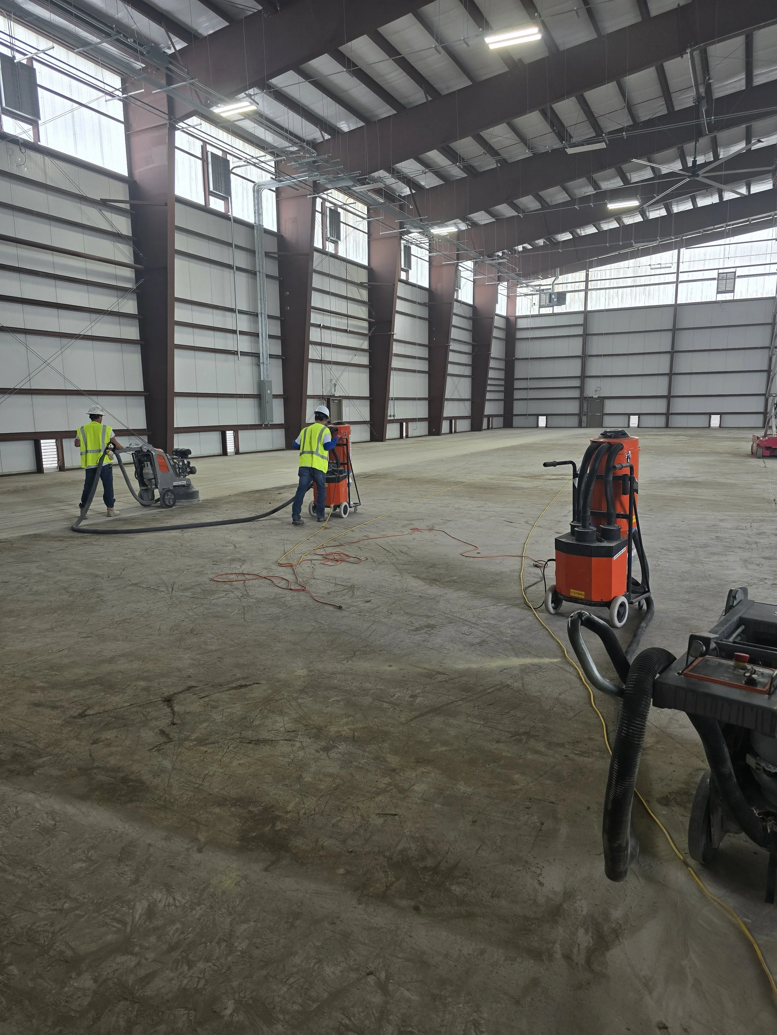 Flooring contractors working on a large commercial concrete floor.