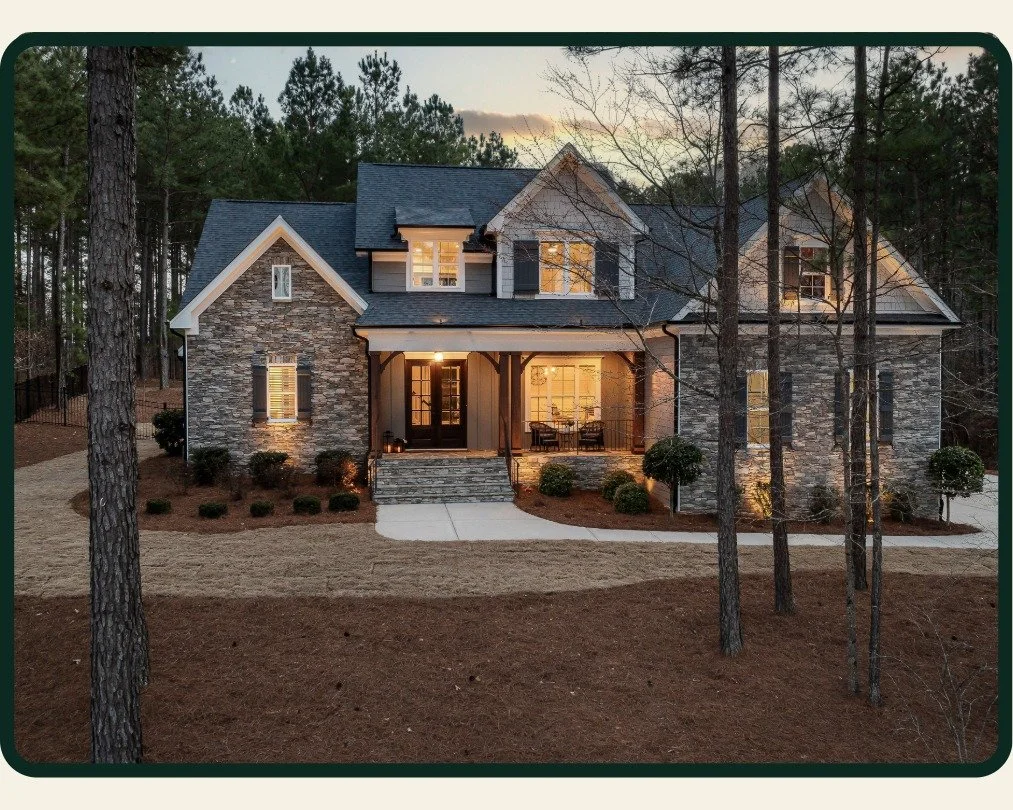 Beautiful stone sided home with a porch in dusk with newly installed asphalt shingle roof  by McMurray and Sons Roofing