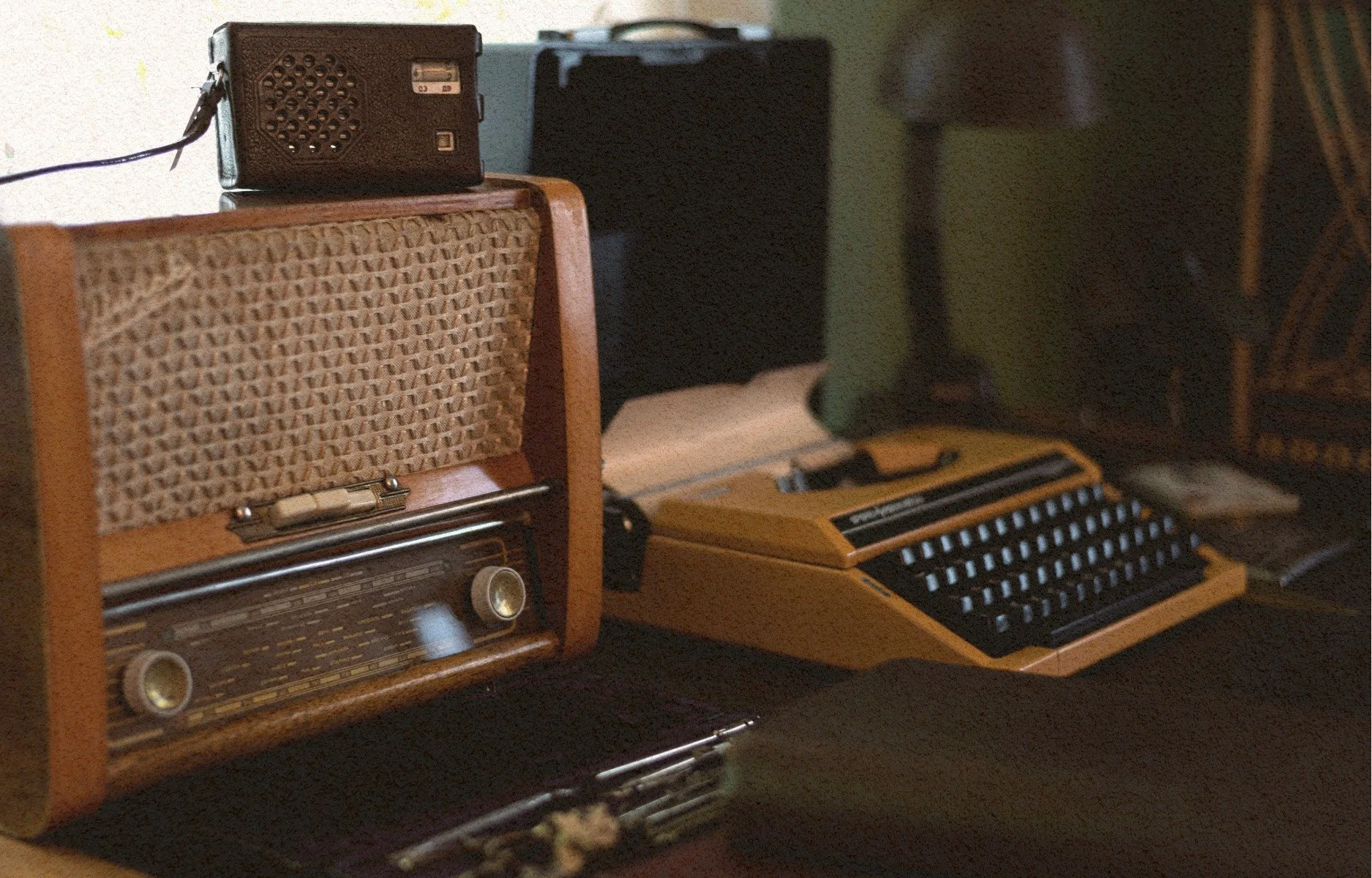 A collection of vintage radios and a vintage typewriter on a dark surface.