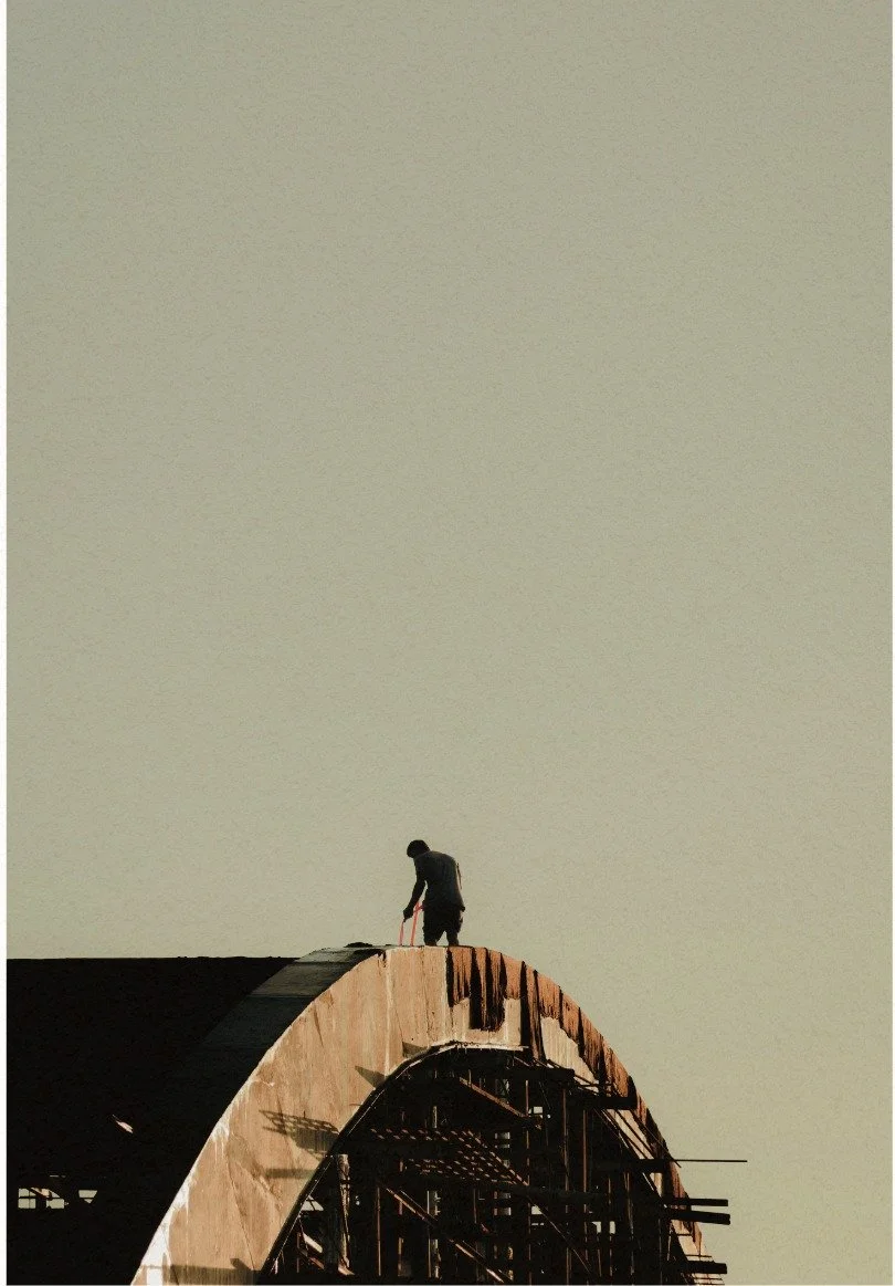 A roofing company worker on a arched roof installing roofing panels