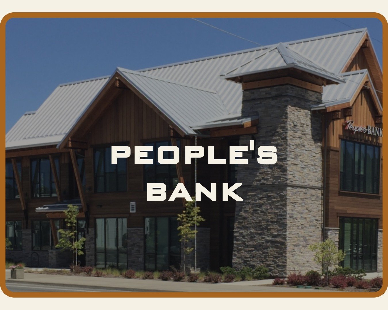 Metal roof and building of People's Bank in Grants Pass Oregon surrounded by landscaping.
