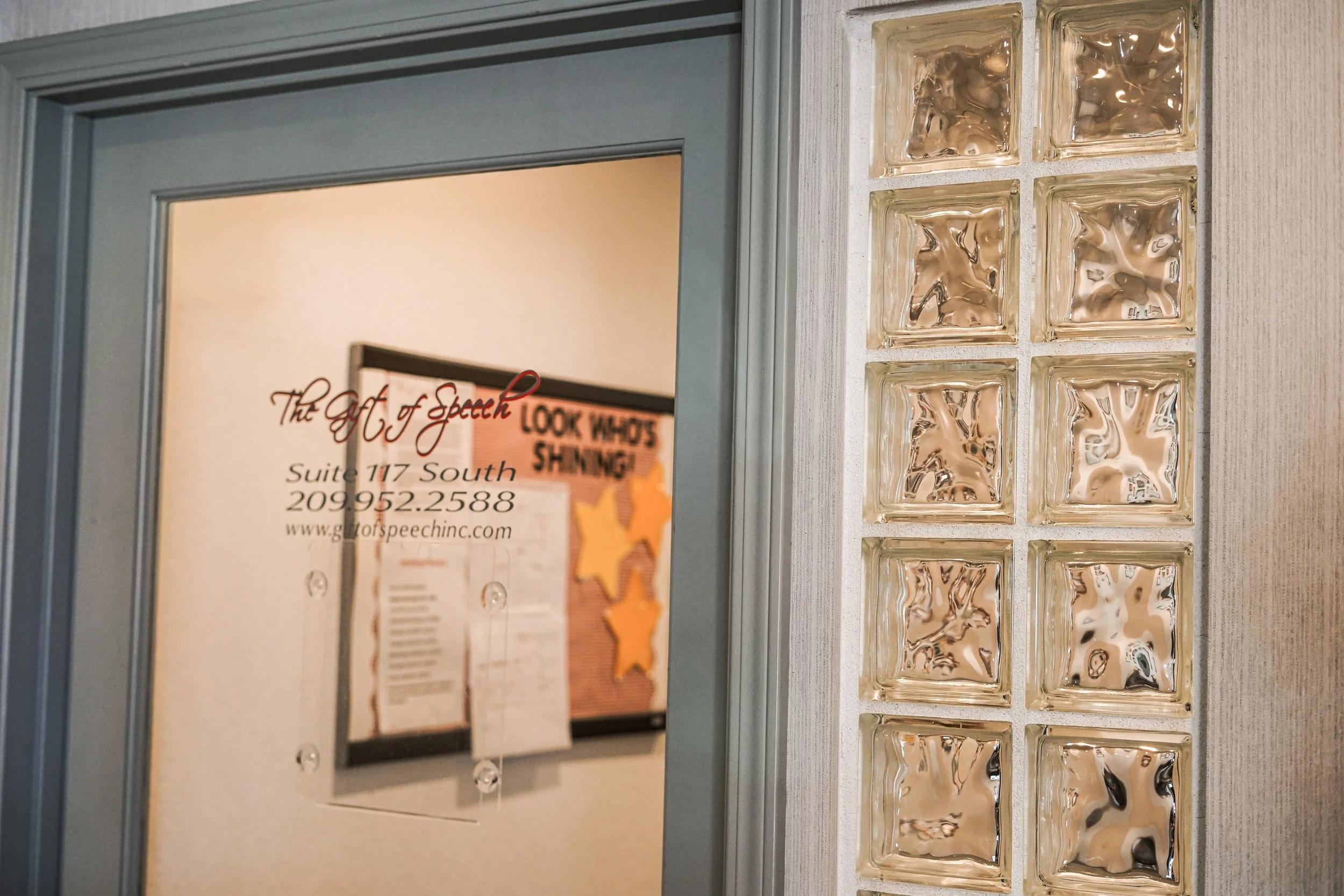 Part of an office door with a sign and decorative glass blocks on the right side.