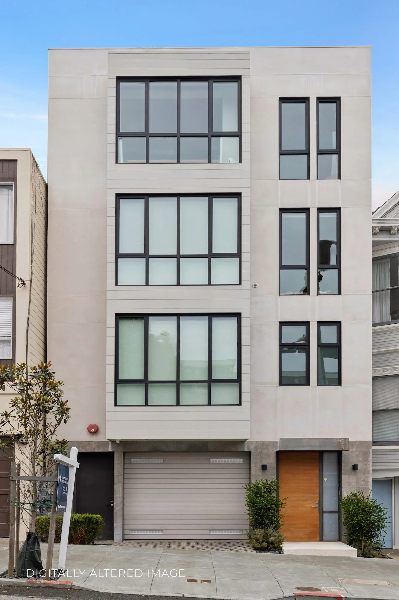 Modern multi-story building with large rectangular windows, a garage door, and a wooden front door, with a small tree and plants in front.