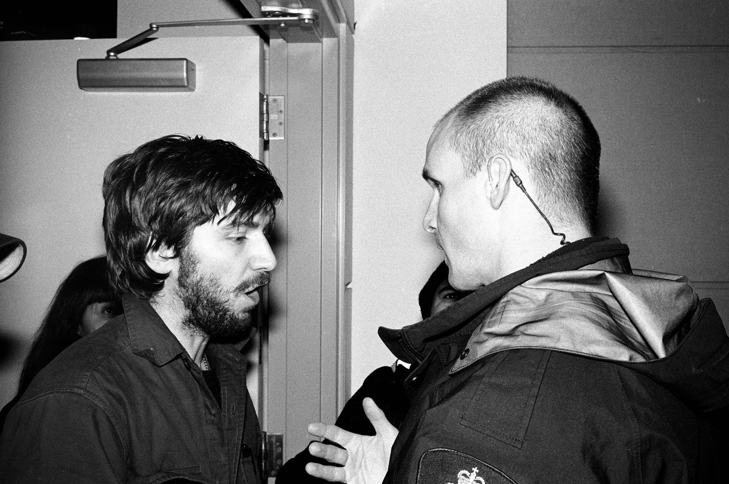 Two men in conversation inside a doorway, black and white photograph.