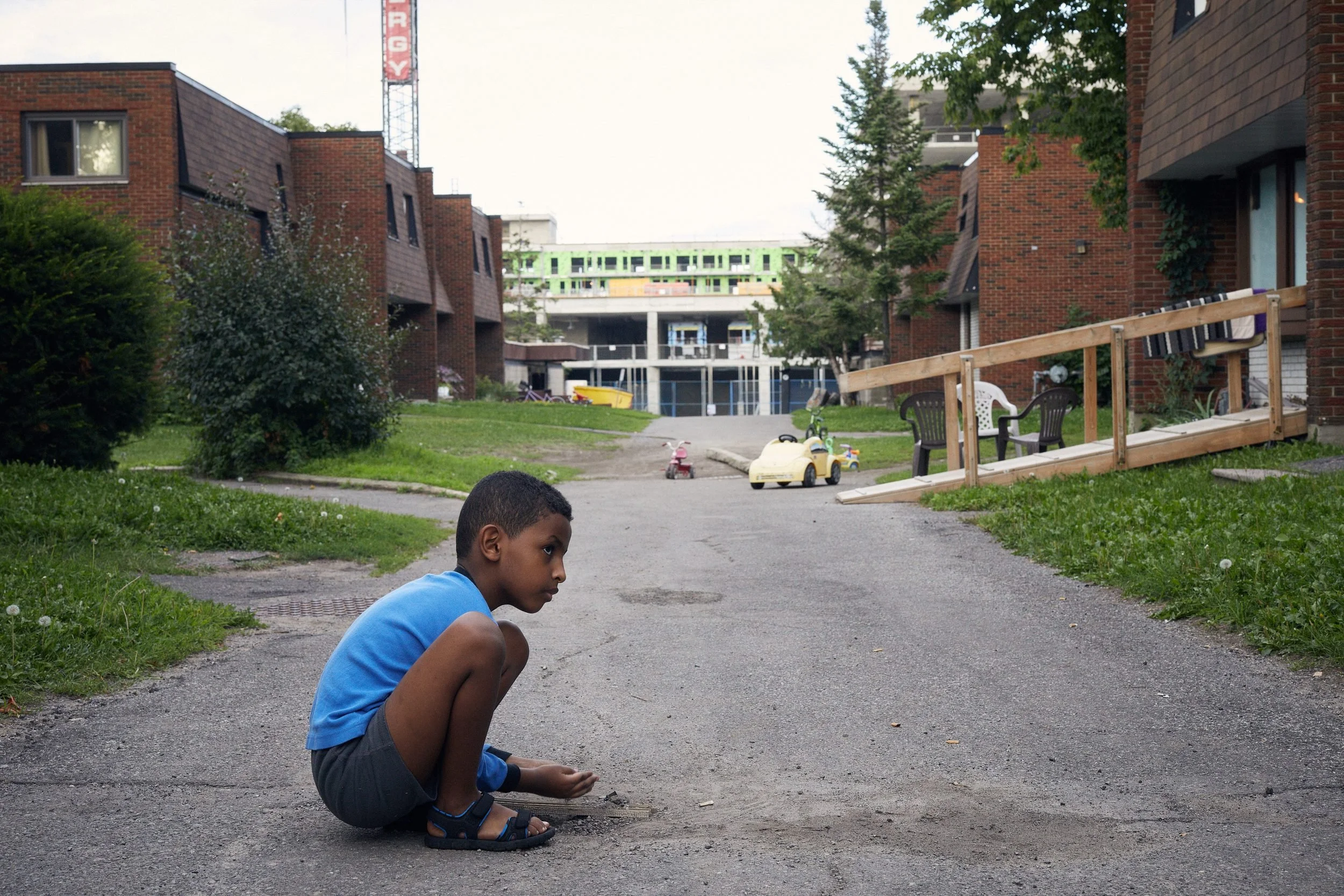 Young boy plays in the asphalt walkway, Herongate, Ottawa. 2018.