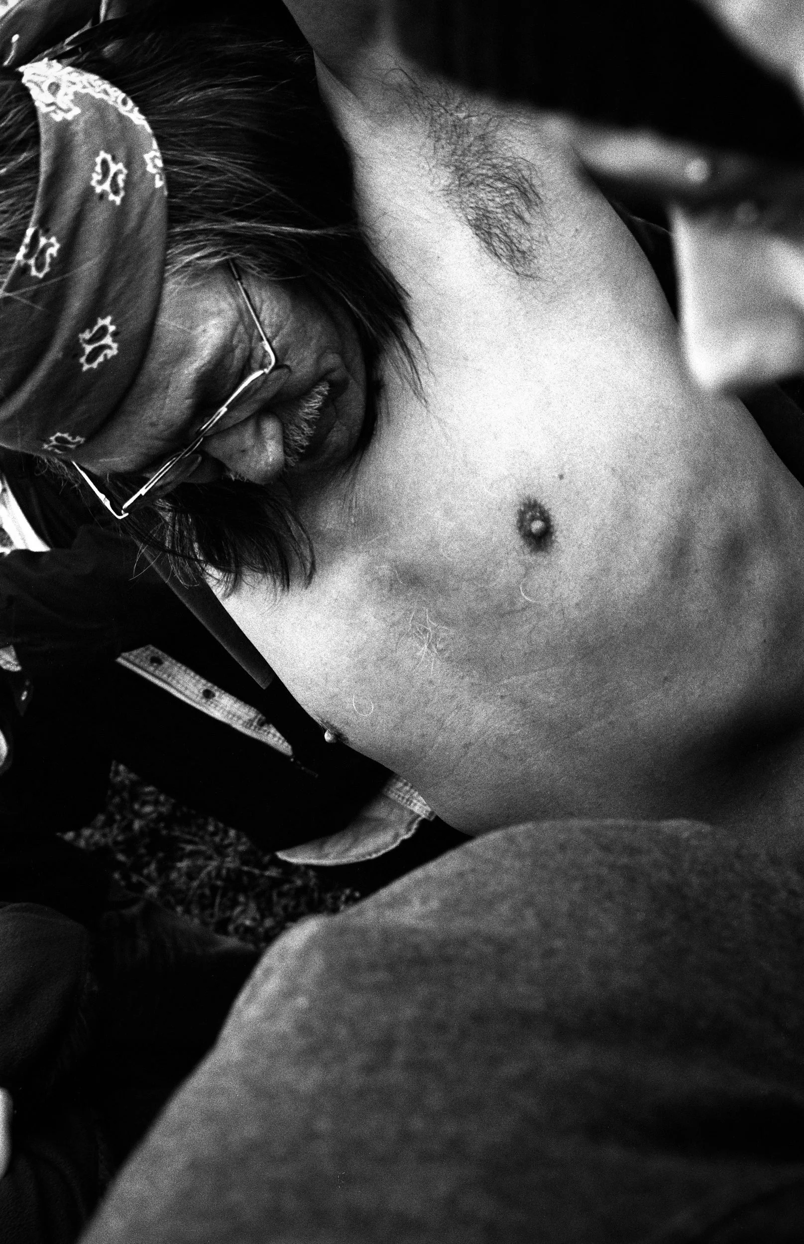 Black and white photograph of a person in close-up, wearing patterned clothing and sunglasses.