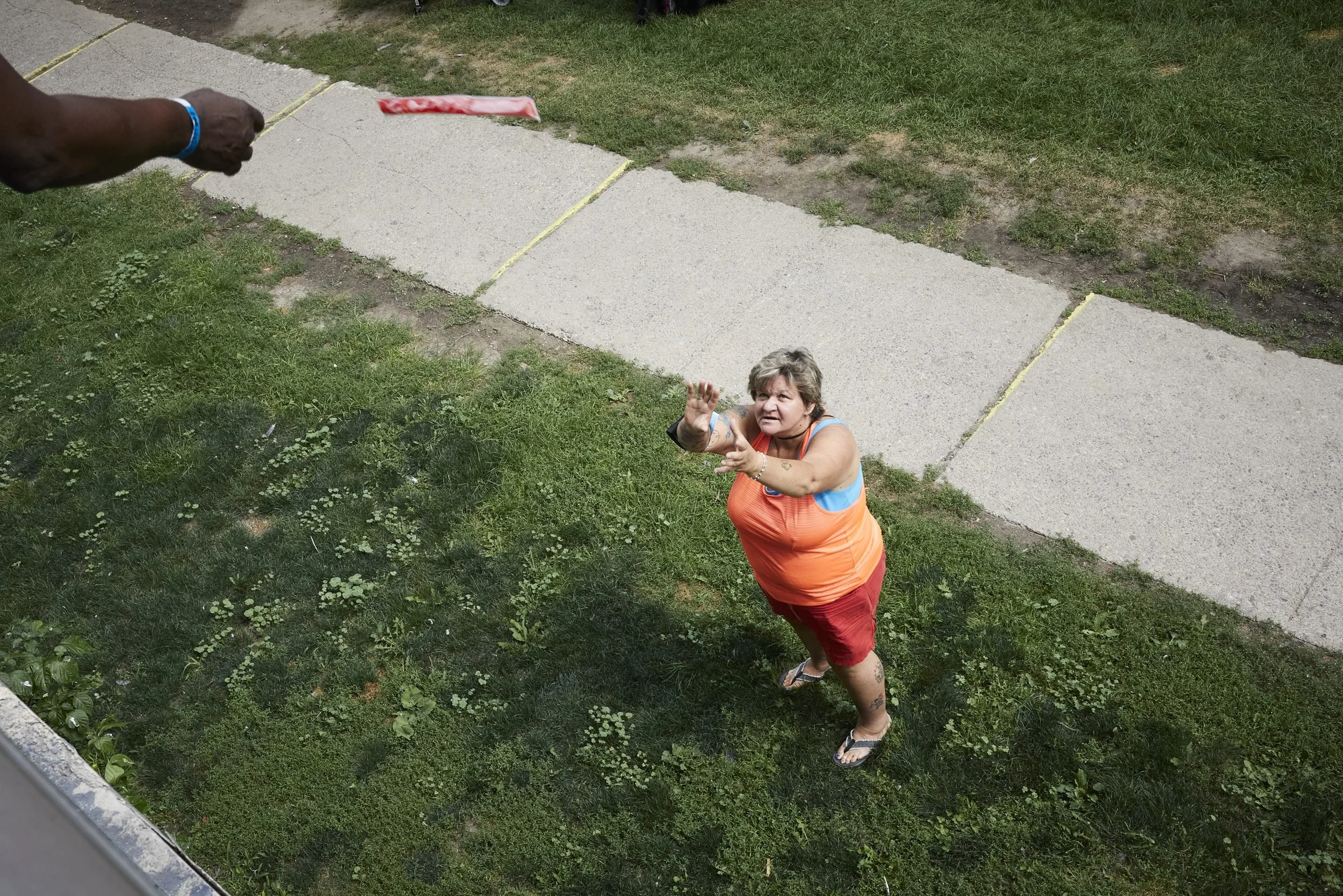 West Lodge resident and tenant organizer Petra Peters receives a freezie from the food bank balcony.