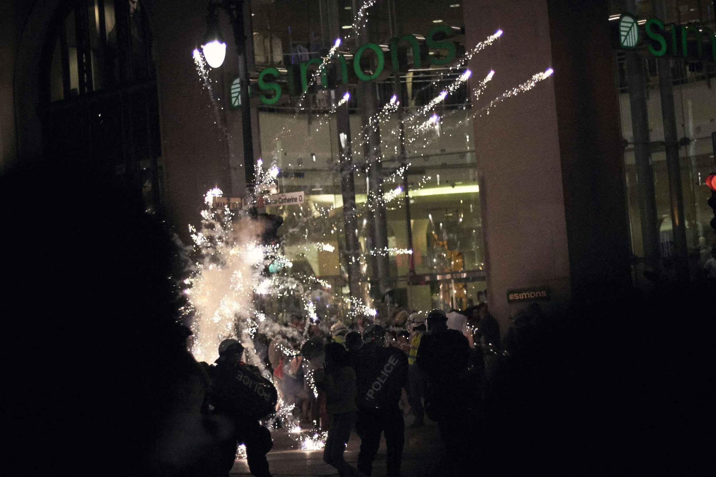 Fireworks explode over the heads of riot police, Quebec Spring, 2012.
