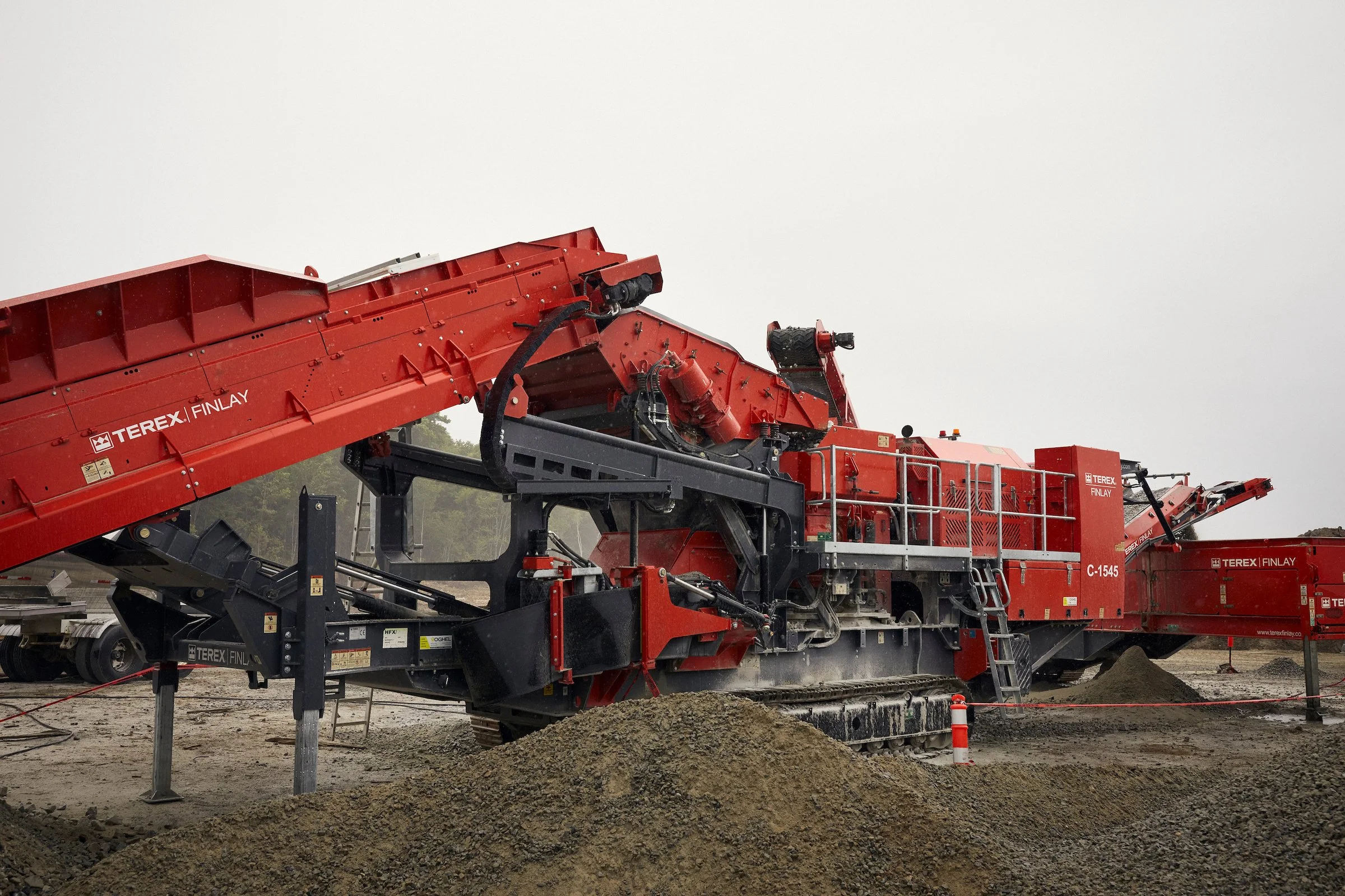 A red Terex Finlay mobile crusher and conveyors at Nouveau Monde Graphite, Saint-Michel-des-Saints, Quebec.