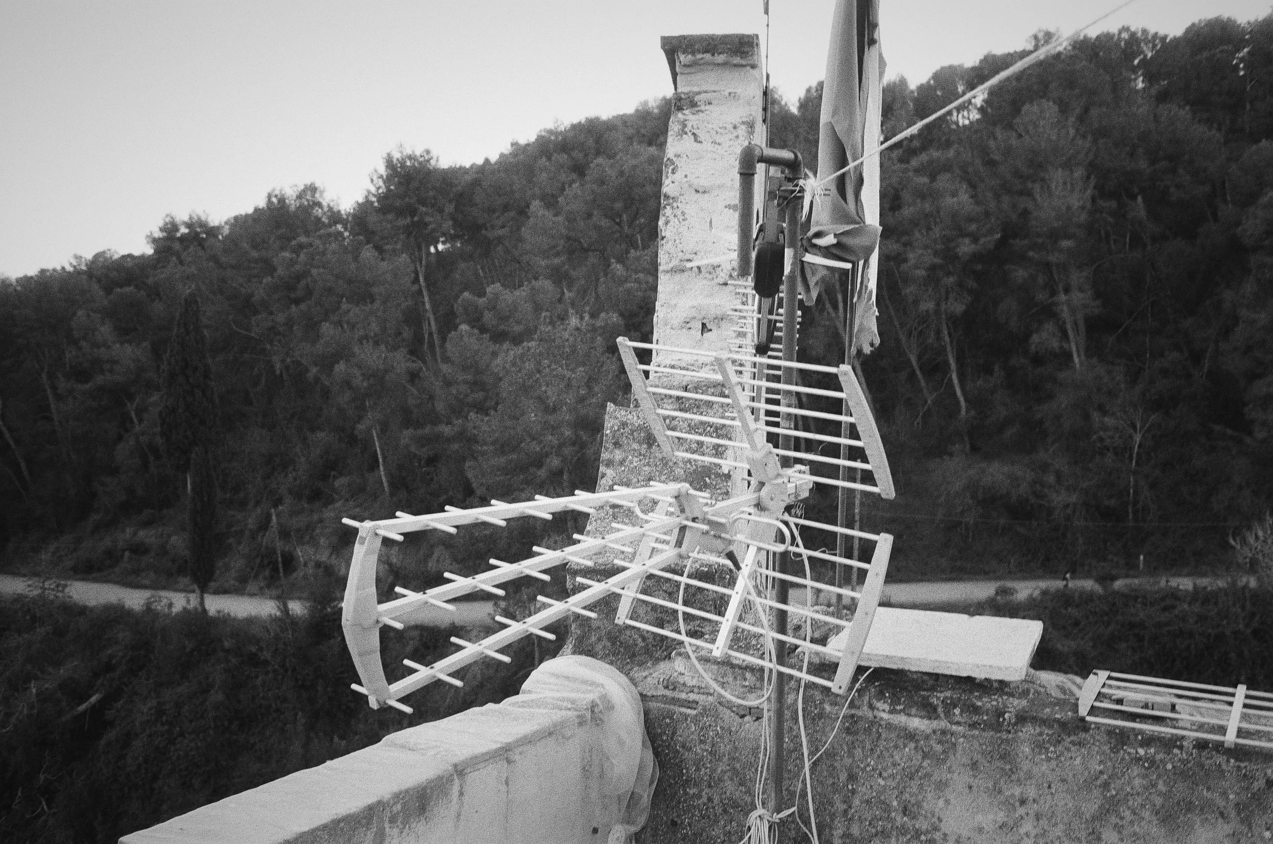 Solar panels and wind turbine mounted on a concrete structure overlooking a forested valley.