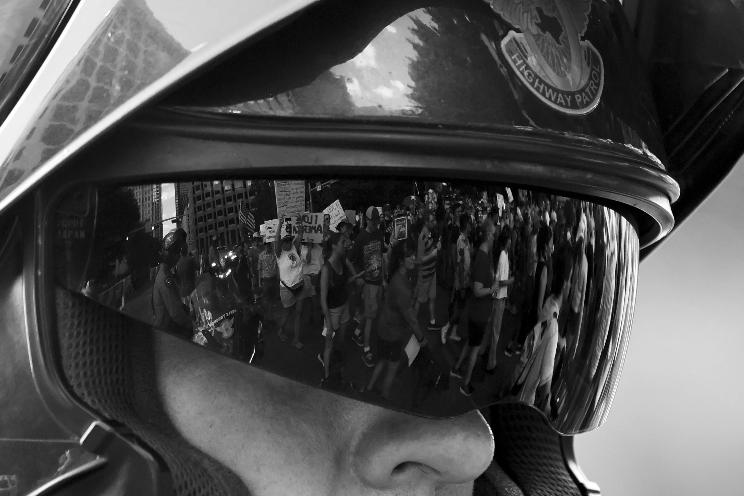 A Austin highway patrol officer's visor reflects the No Kings Protest participants marching down Congress St. in Austin, Texas on Oct. 18, 2025.