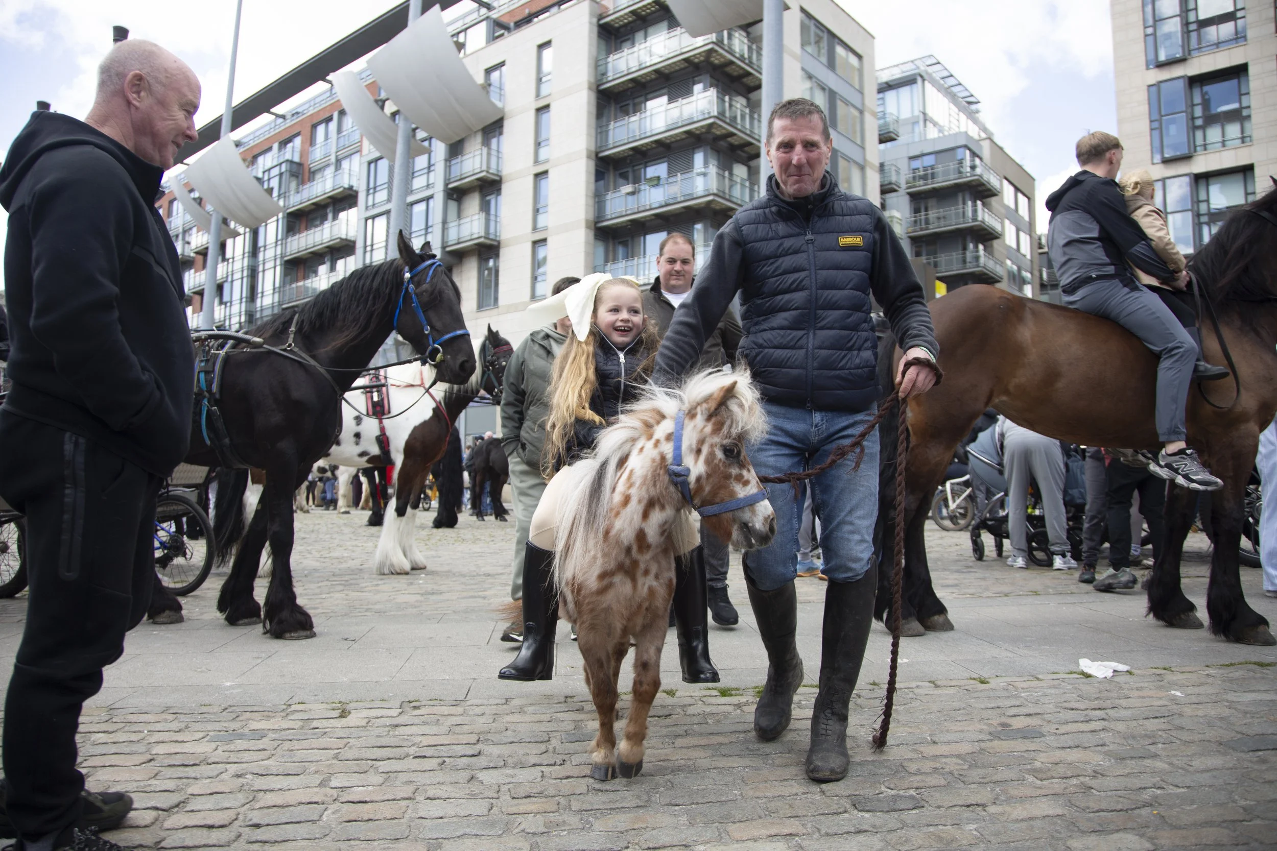Philip Kavanagh walks his miniature pony with a family friend's daughter at the Smithfield Horse Fair in Dublin, Ireland on Sunday, May 10, 2026. Participants claim that most of the children in attendance own their own horse or pony, and are typicall
