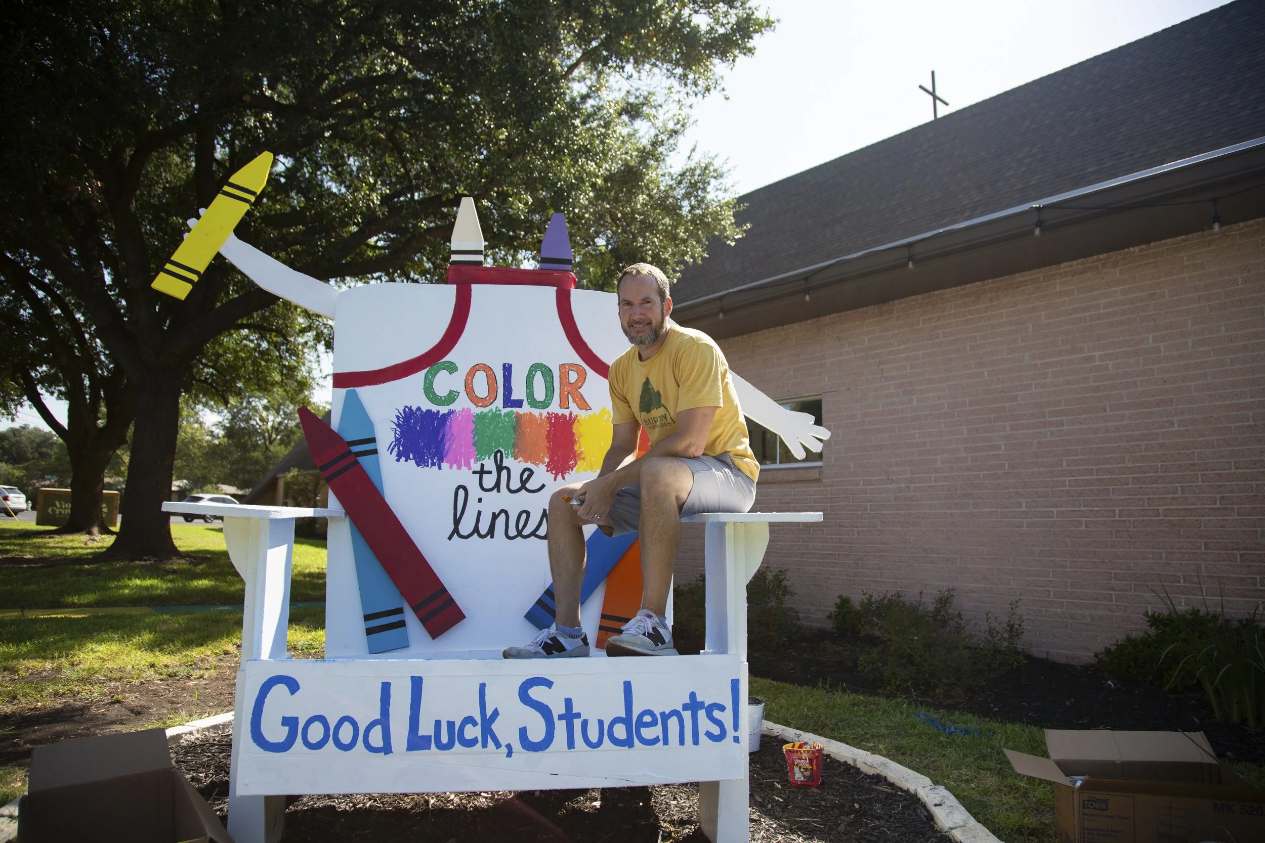 Jay Cooper, pastor at Violet Crown City Church, paints a Adirondack chair outside the church in Austin, Texas on August 7, 2026.  