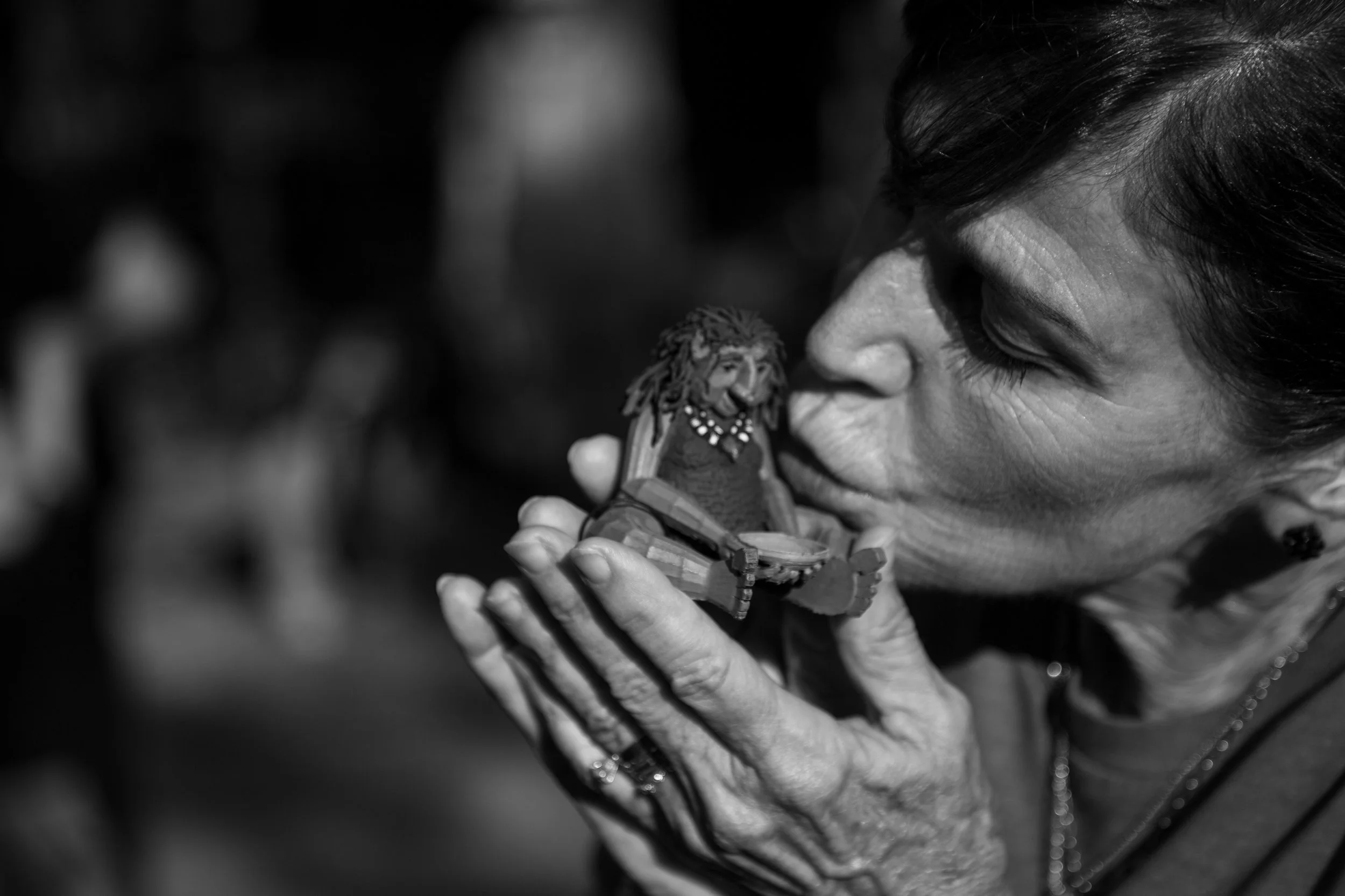 Lynne Dobson, kisses a wooden mini figurine of Malin at her memorial service at Pease Park on Wednesday, June 24, 2026. Lynne was gifted the figurine by artist Jackson Branscum.