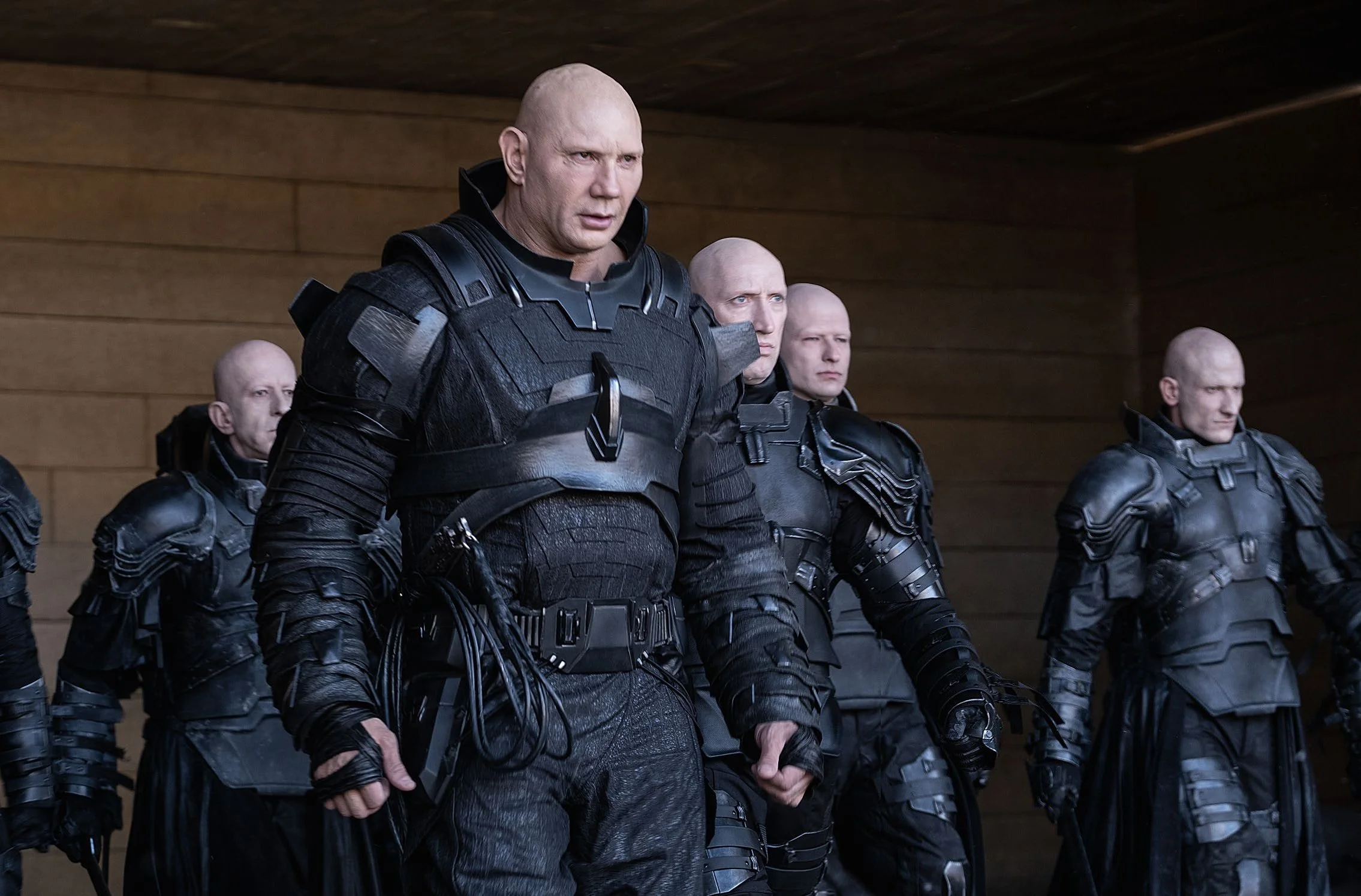 Scene from "Dune" the movie. A group of men in black tactical armor standing in formation indoors.