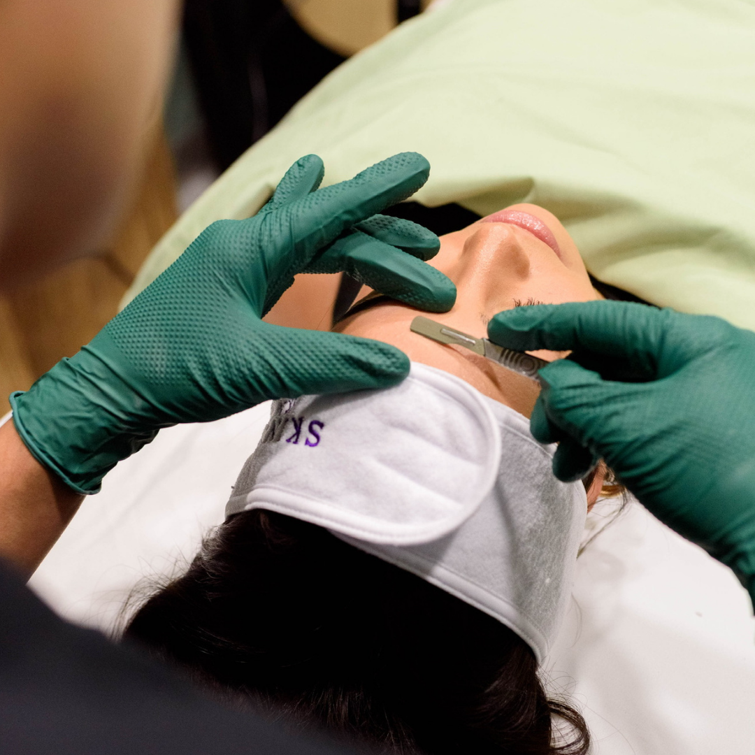 A person receiving a facial injection with a hypodermic needle while lying down with a face mask covering their eyes.