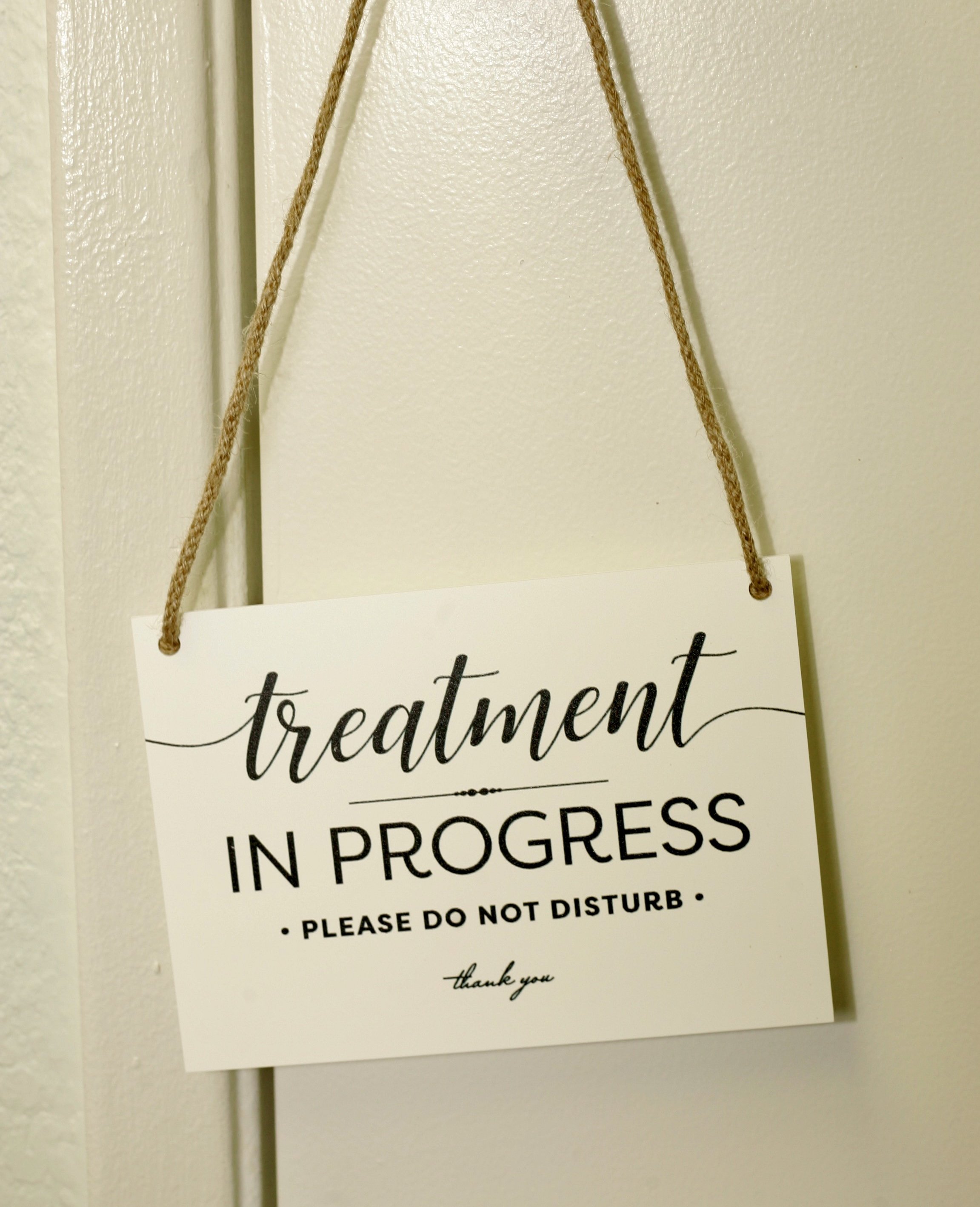 A sign hanging by a string that reads, 'to treatment in progress. Please do not disturb. Thank you.'