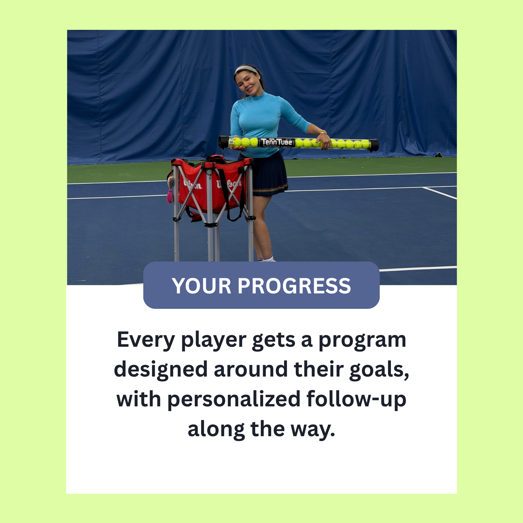 A woman holding tennis balls in a tube on an indoor tennis court surrounded by a blue curtain.
