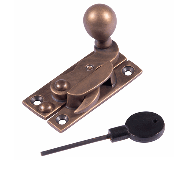 A brass latch with a round knob, a latch lever, and a black plastic key with a long metal shaft.