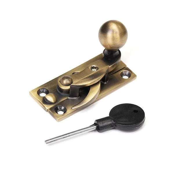 A brass latch with a round knob, a latch lever, and a black plastic key with a long metal shaft.