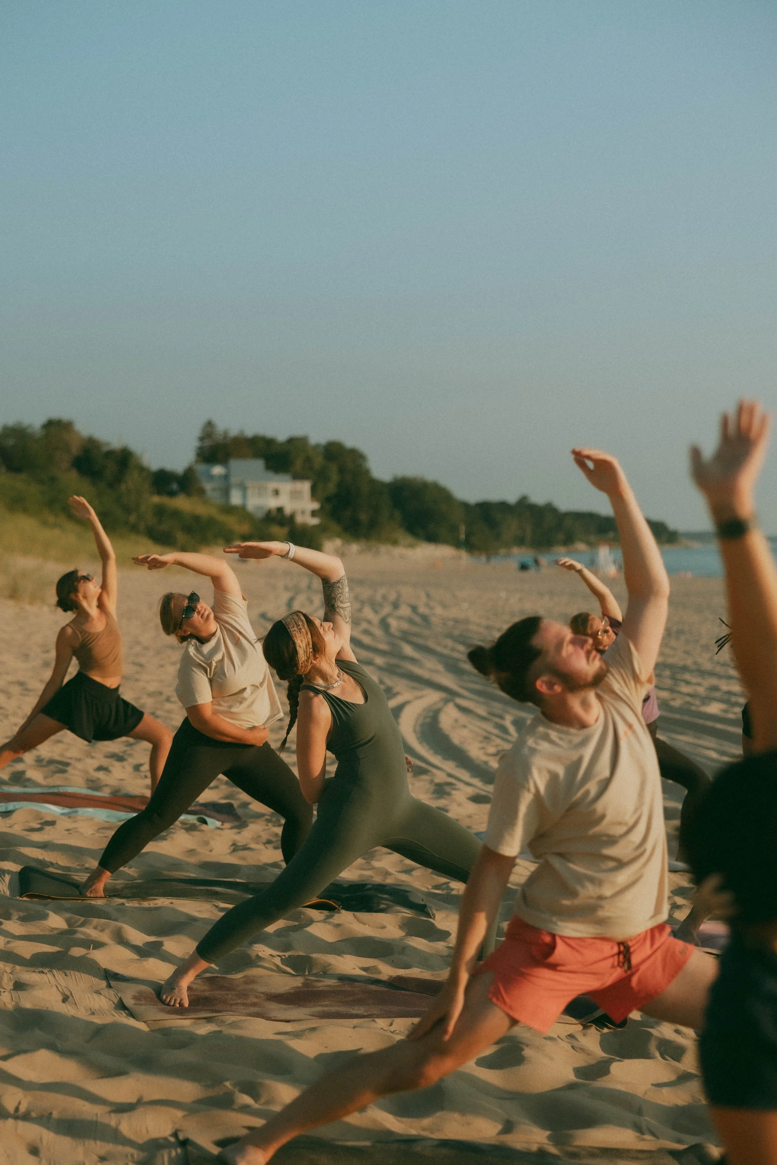 People practicing yoga on the beach during sunset