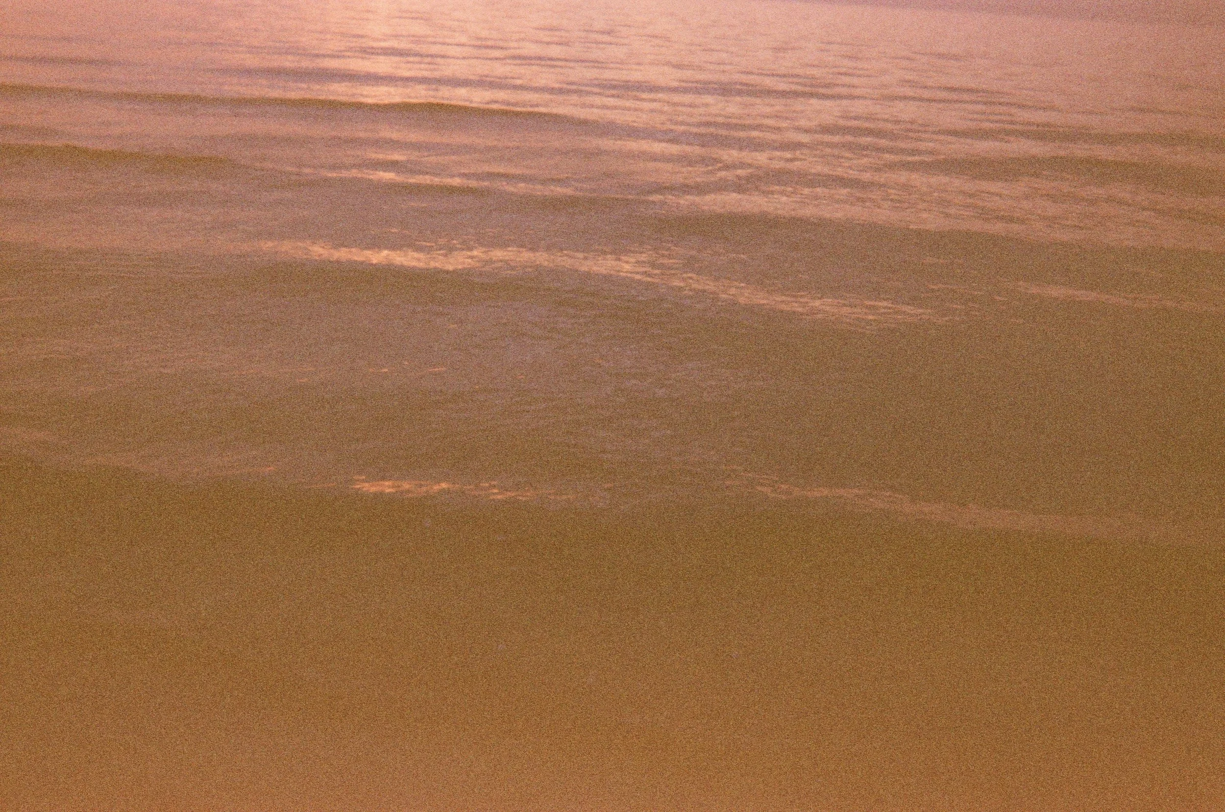 A sunset over Lake Michigan with pink and orange clouds reflecting on the water.