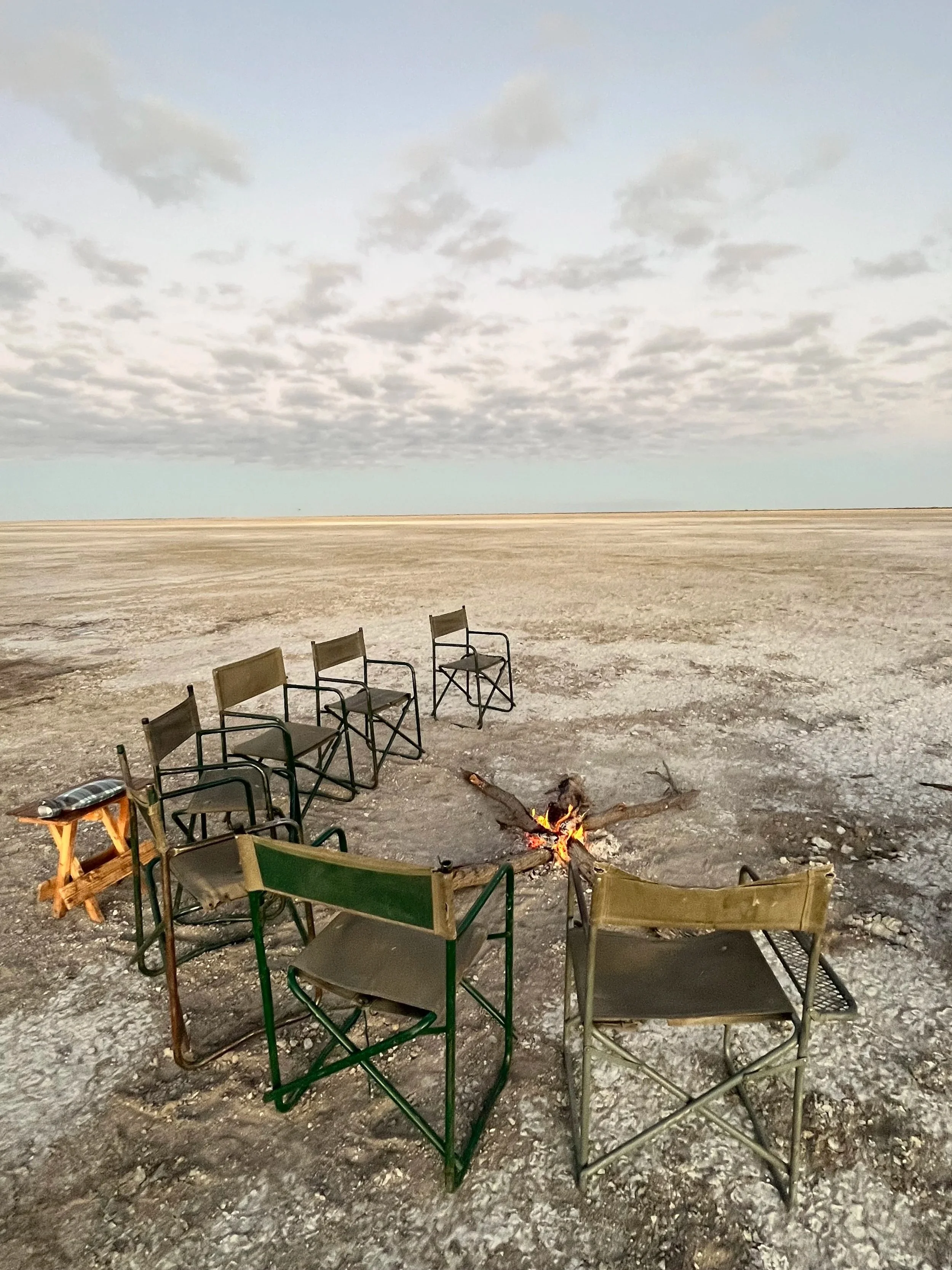 Camp chairs arranged in a seim-circle around a fire on the Makgadikgadi Salt Pans, Botswana.