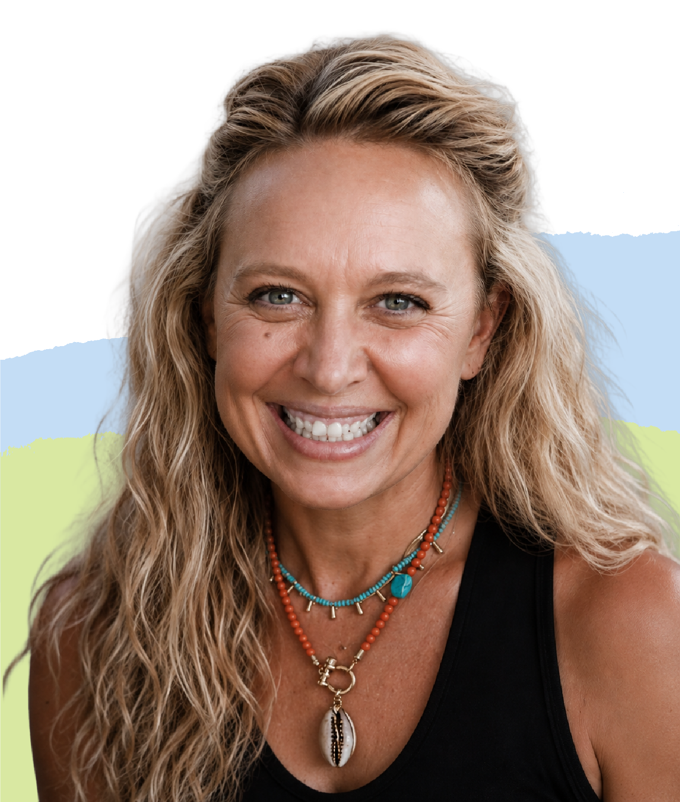 Portrait of a smiling woman with long, curly blonde hair, wearing layered beaded necklaces, a black sleeveless top, and colorful jewelry, outdoors with a painted wall background.