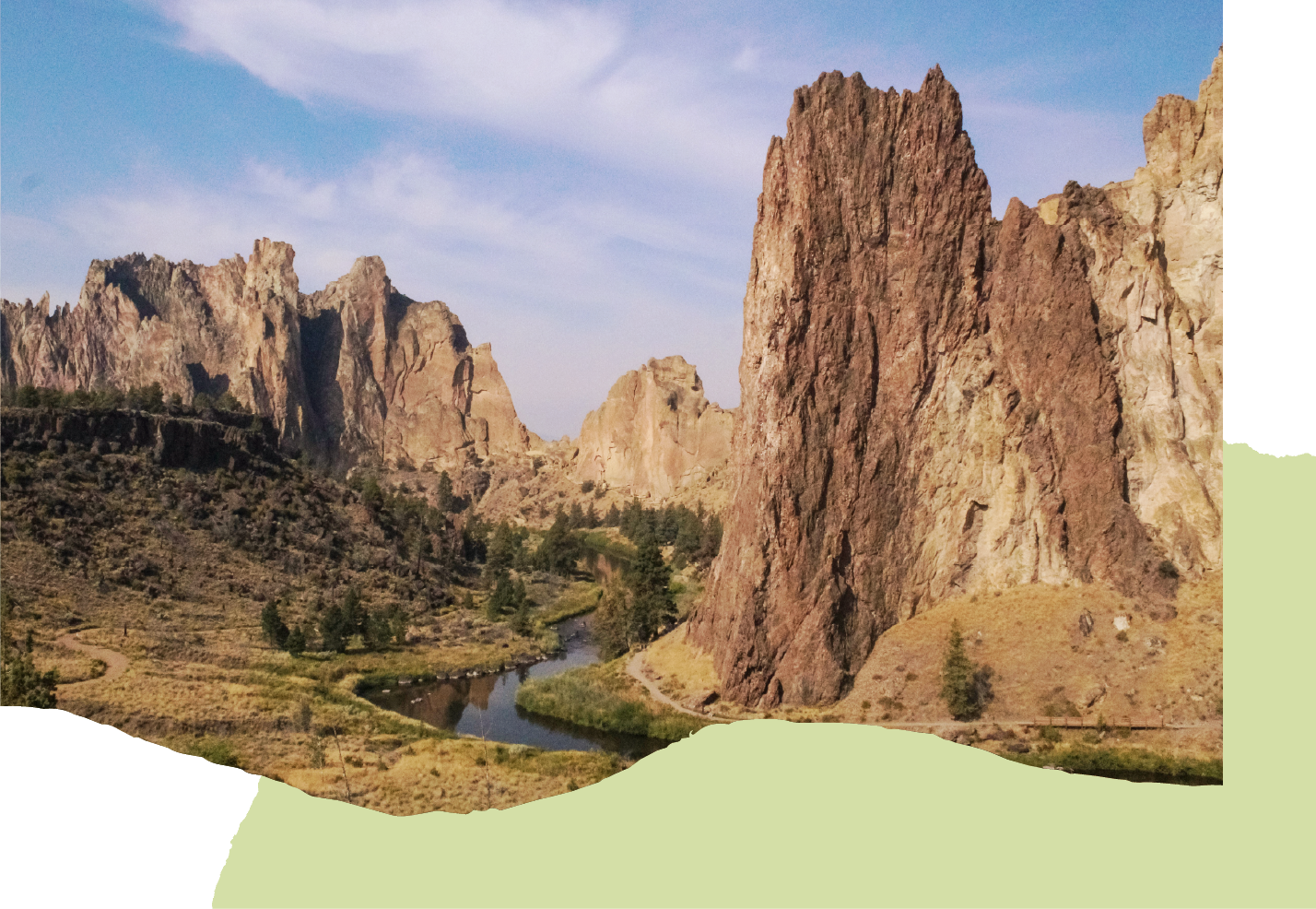 Scenic landscape of tall rugged rock formations, a winding river, and sparse trees under a blue sky.